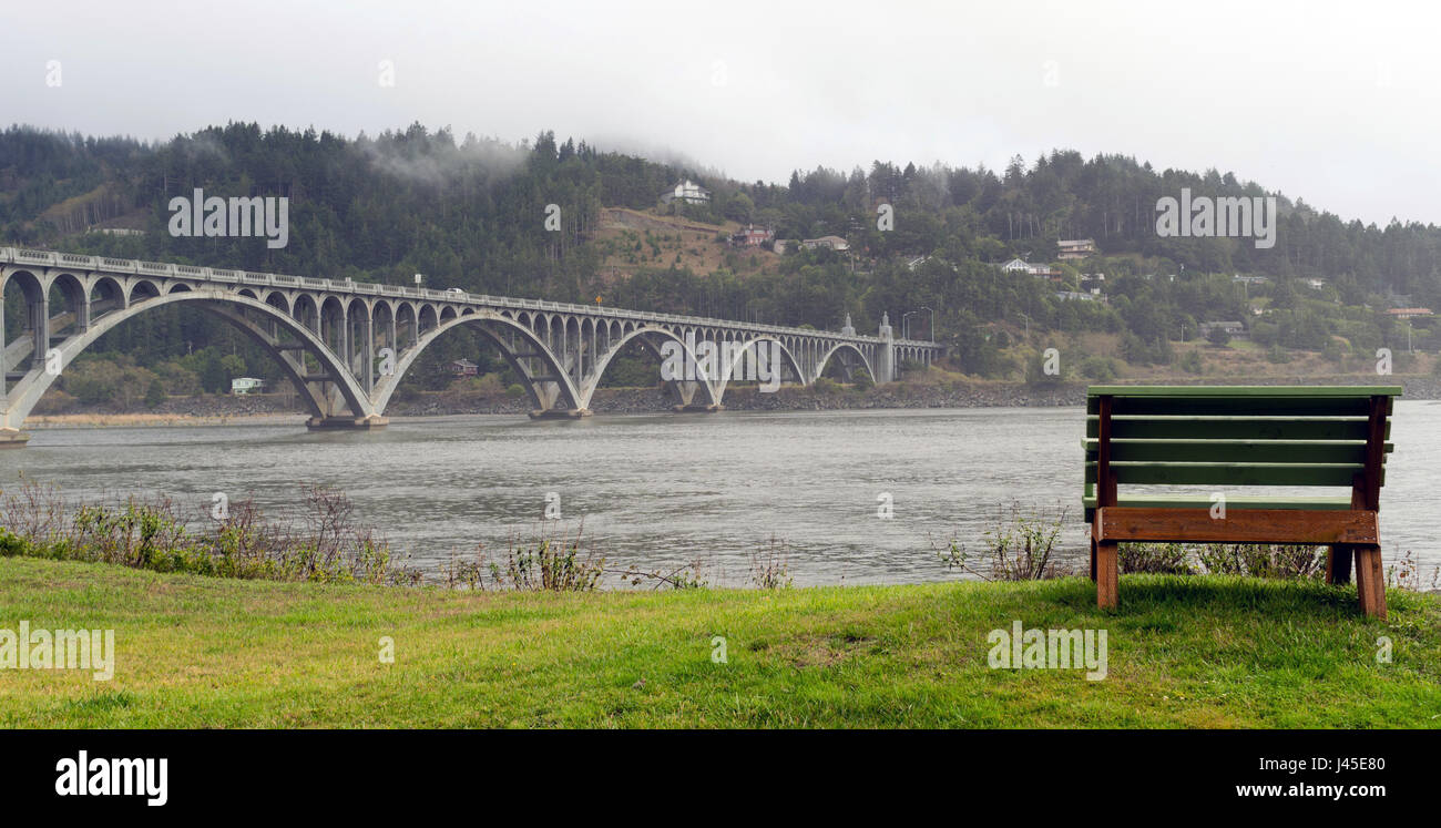 Un banc bien placé se trouve sur le front de mer avec vue sur la traversée de pont Banque D'Images