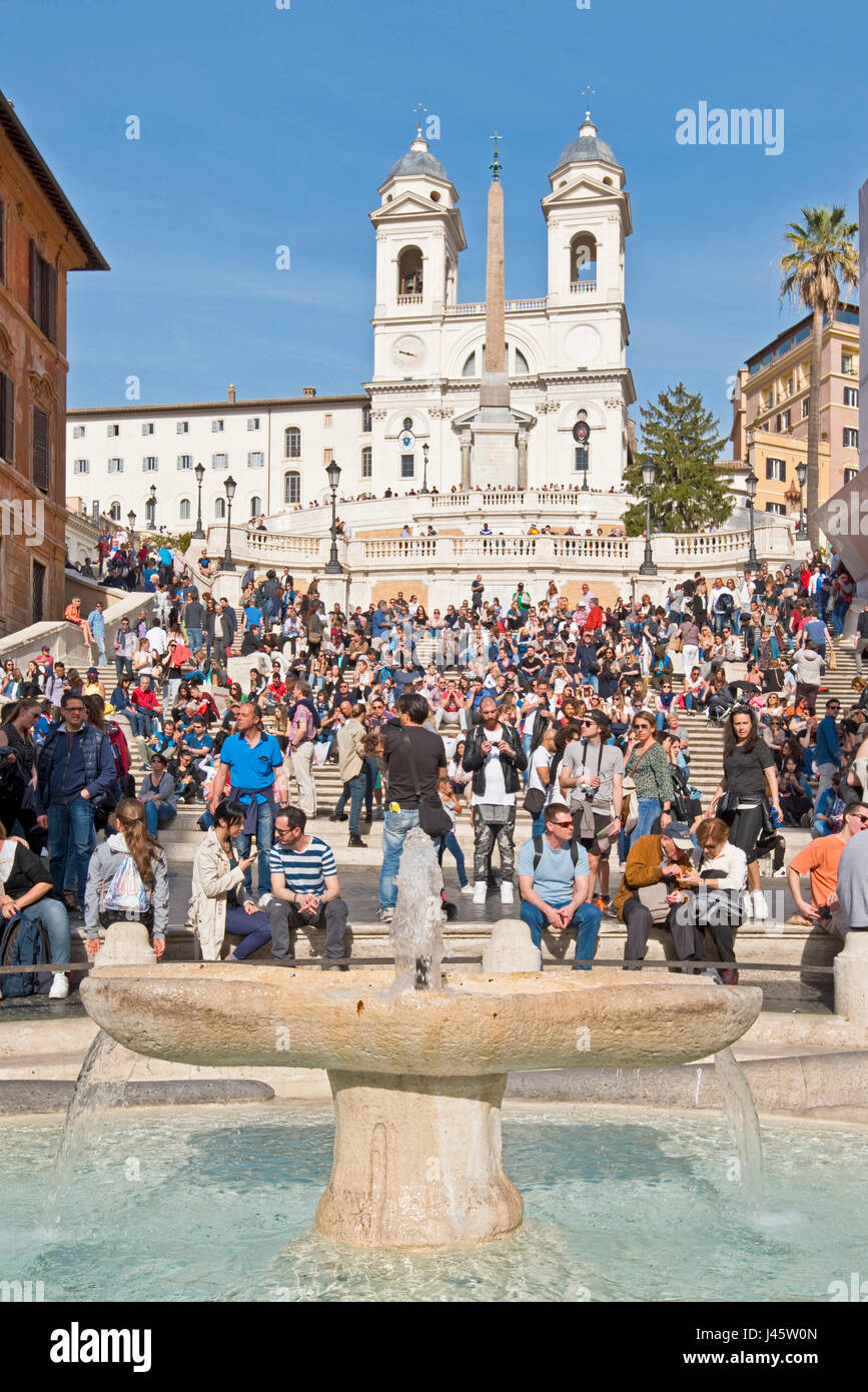 Place d'Espagne à Rome avec les touristes sur une journée ensoleillée avec ciel bleu de l'église Trinità dei Monti en arrière-plan et fontaine de l'affreux voile avant-plan. Banque D'Images