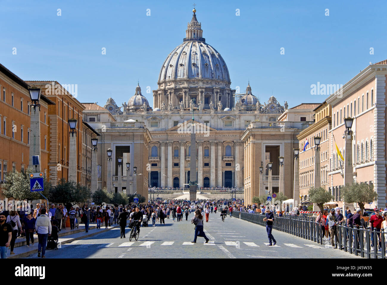 Vue perspective du comprimé de la Basilique St Pierre à Rome lors d'une journée ensoleillée avec ciel bleu et des foules de touristes avant-plan. Banque D'Images