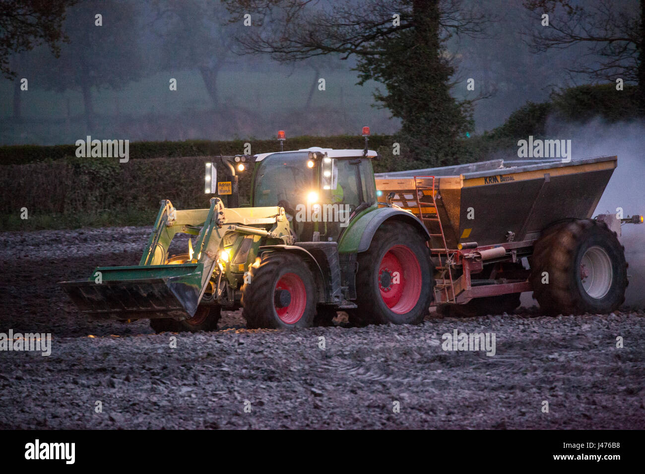 Agriculteur travailler jusque tard dans la nuit, l'épandage de chaux par ses feux du tracteur Banque D'Images