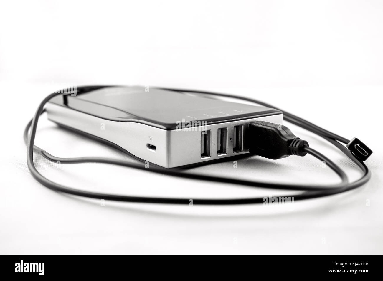 Powerbank noir isolé avec câble USB branché Banque D'Images