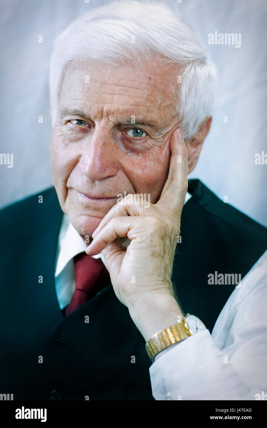 Vieil homme avec d'épais cheveux blancs portant un costume bleu avec une cravate  rouge et or watch posés avec sa main posée sur son visage Photo Stock -  Alamy