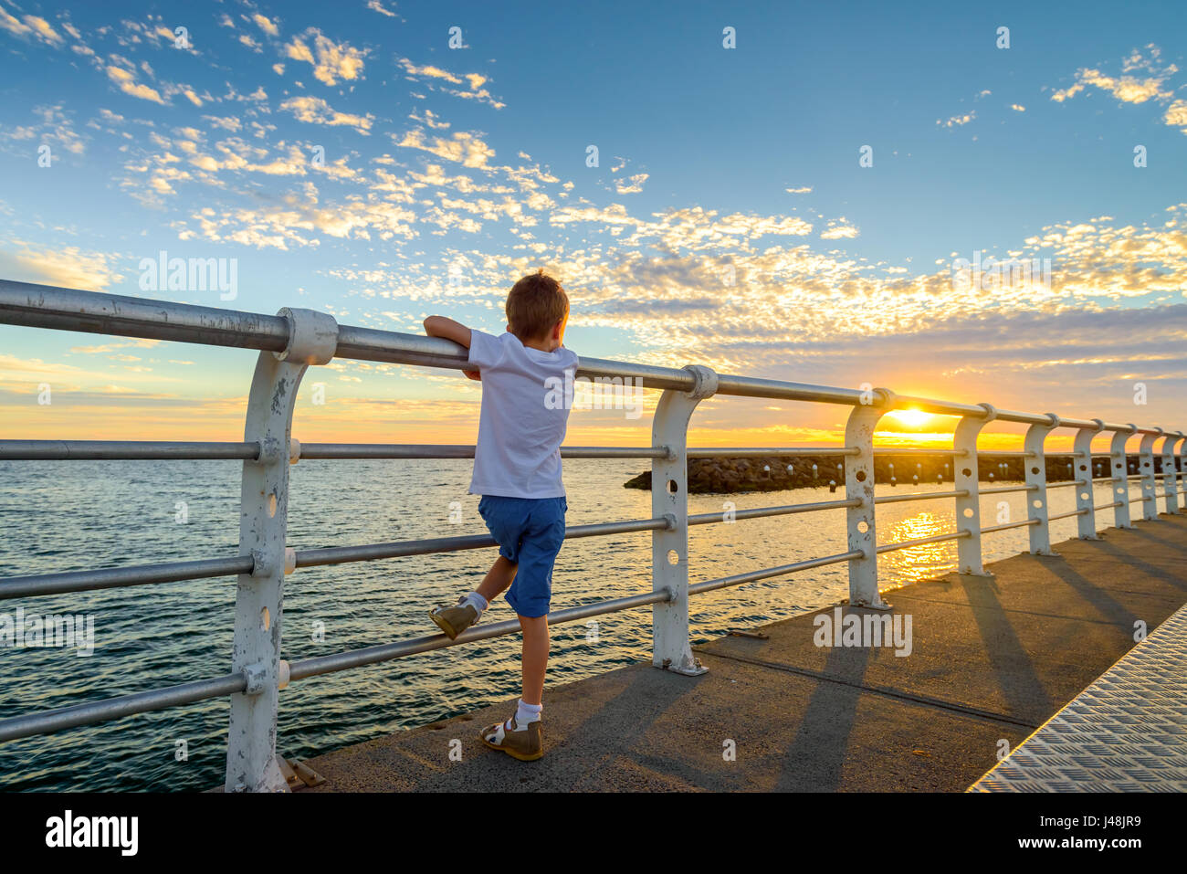 Garçon regardant le coucher du soleil à partir de la jetée de St Kilda Melbourne, Victoria, Australie Banque D'Images