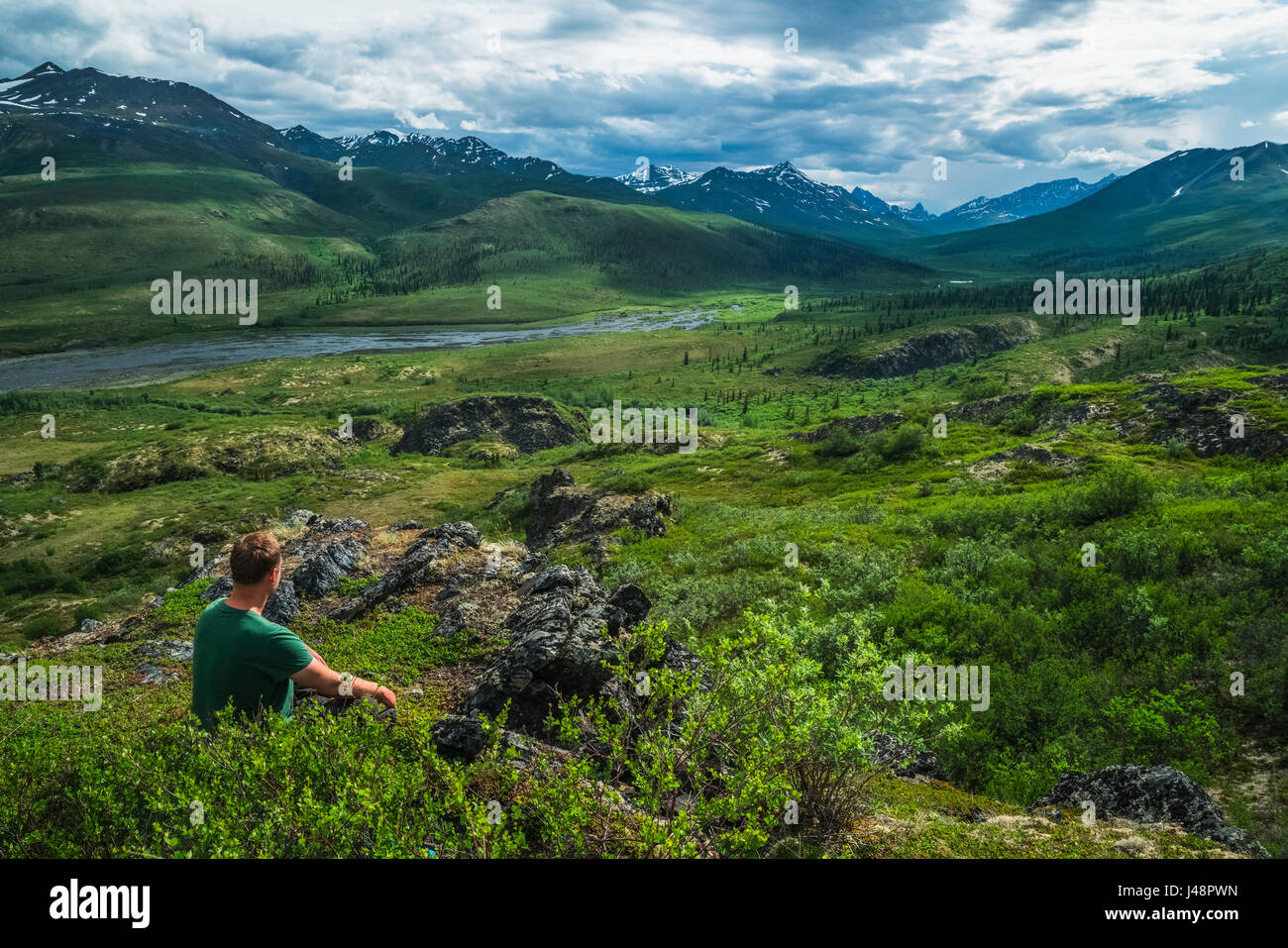 Homme assis avec vue sur la vallée du Klondike le long de la route Dempster ; Yukon, Canada Banque D'Images