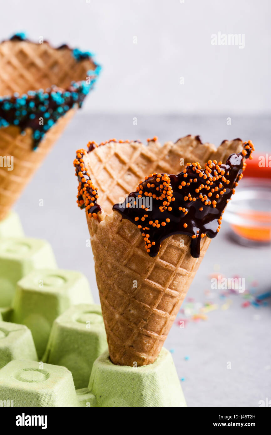 Préparer des cornets de crème glacée au chocolat avec des bonbons décorations sprinkles Banque D'Images