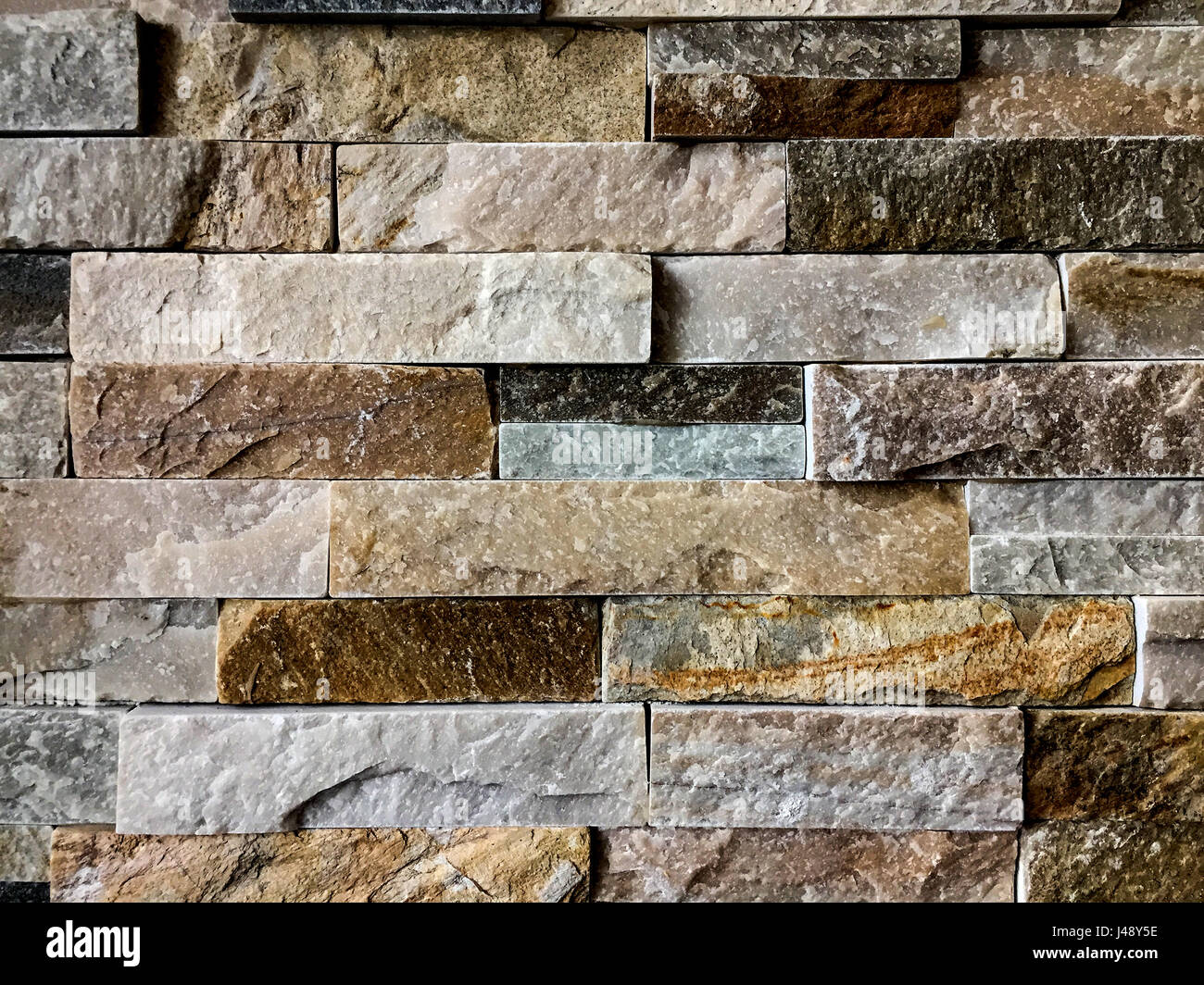 La texture du mur de pierre ou d'arrière-plan avec jaunâtres, noir, gris et blanc Banque D'Images