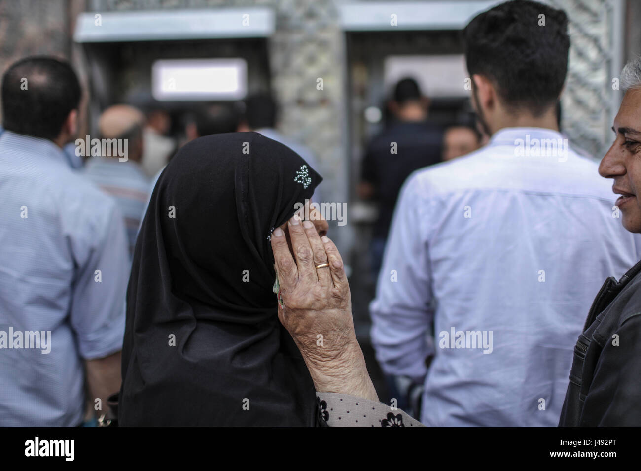 (170510) -- Gaza, 10 mai 2017 (Xinhua) -- Les Palestiniens employés par l'Autorité nationale palestinienne (ANP) attendre de recevoir leurs salaires à un guichet automatique à l'extérieur d'une banque dans la ville de Gaza, le 10 mai 2017. Les salaires des fonctionnaires palestiniens et d'anciens agents de sécurité dans la bande de Gaza ont été réduites d'environ 30 pour cent pour le deuxième mois consécutif depuis que l'Autorité nationale palestinienne (ANP) Gouvernement de consensus a rendu la décision à Ramallah le 4 avril. (Xinhua/Wissam Nassar) Banque D'Images