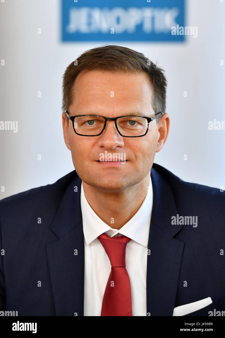 Jena, Allemagne. Le 11 mai, 2017. Stefan Traeger, nouveau président du conseil de surveillance lors de Jenoptik AG, représenté à la face d'un logo d'entreprise à Jena, Allemagne, 11 mai 2017. Photo : Martin Schutt/dpa-Zentralbild/dpa/Alamy Live News Banque D'Images