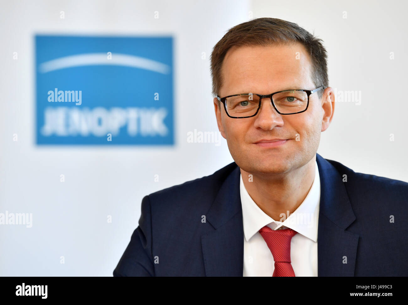 Jena, Allemagne. Le 11 mai, 2017. Stefan Traeger, nouveau président du conseil de surveillance lors de Jenoptik AG, représenté à la face d'un logo d'entreprise à Jena, Allemagne, 11 mai 2017. Photo : Martin Schutt/dpa-Zentralbild/dpa/Alamy Live News Banque D'Images