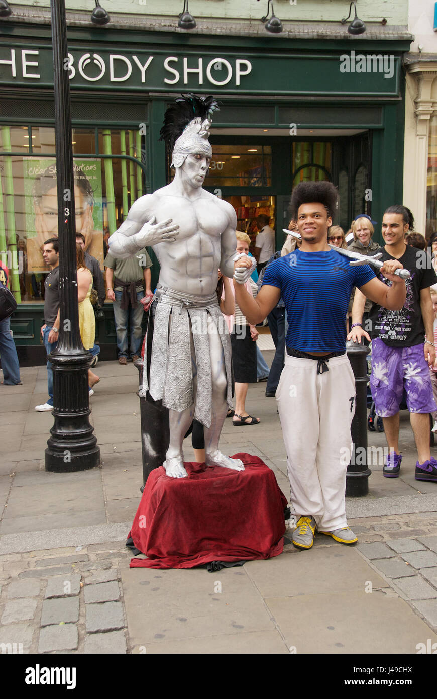 Groupe de jeunes danseurs interagissant avec un artiste de rue sur les rues de Londres, Royaume-Uni Banque D'Images