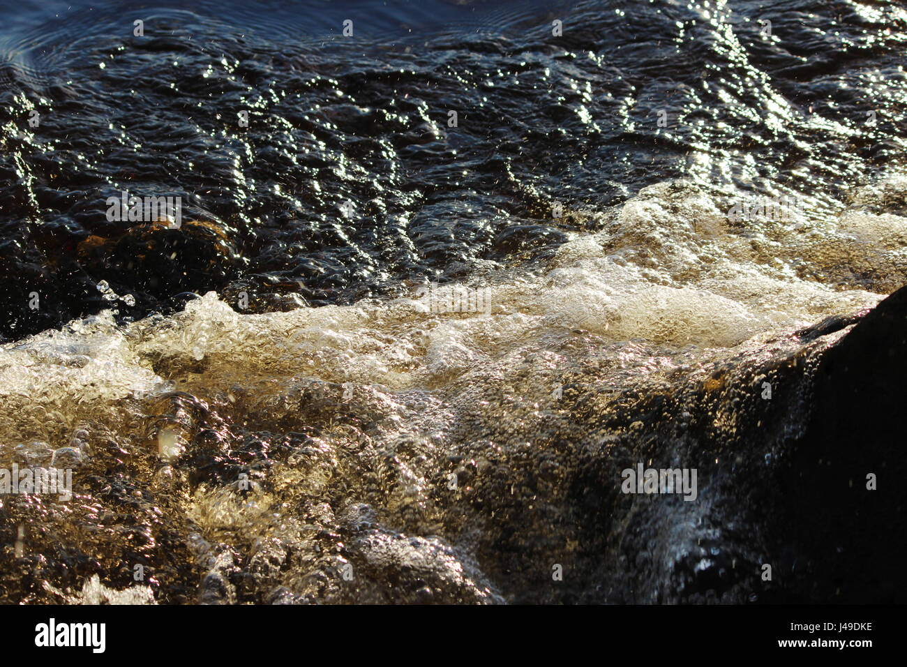 La rivière de l'eau brune du nord de la rivière Dvina bat contre la pierre shore Banque D'Images