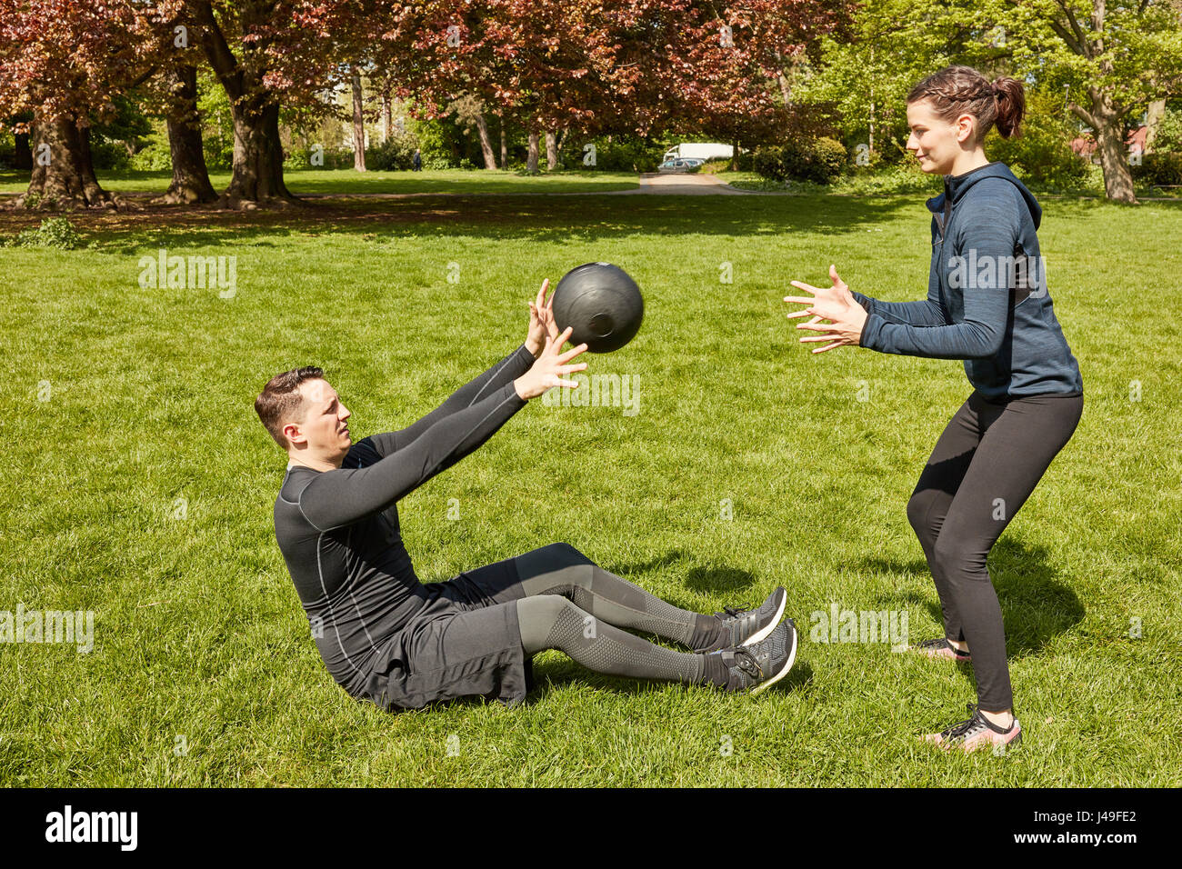 L'homme jette fitness ball à l'entraîneur personnel au parc Banque D'Images