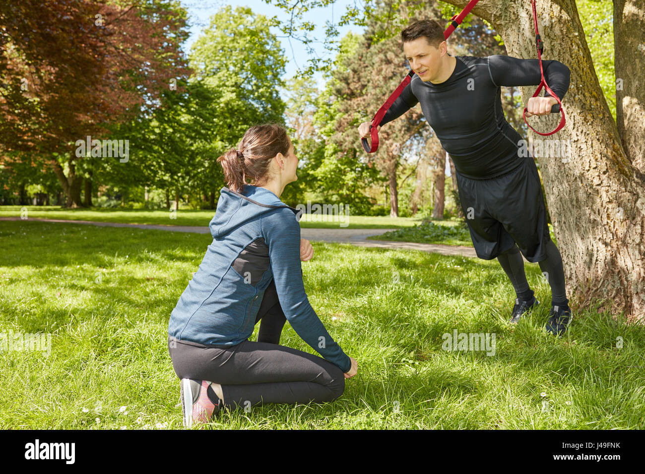 L'élingue de l'homme formation au parc avec fitness trainer Banque D'Images