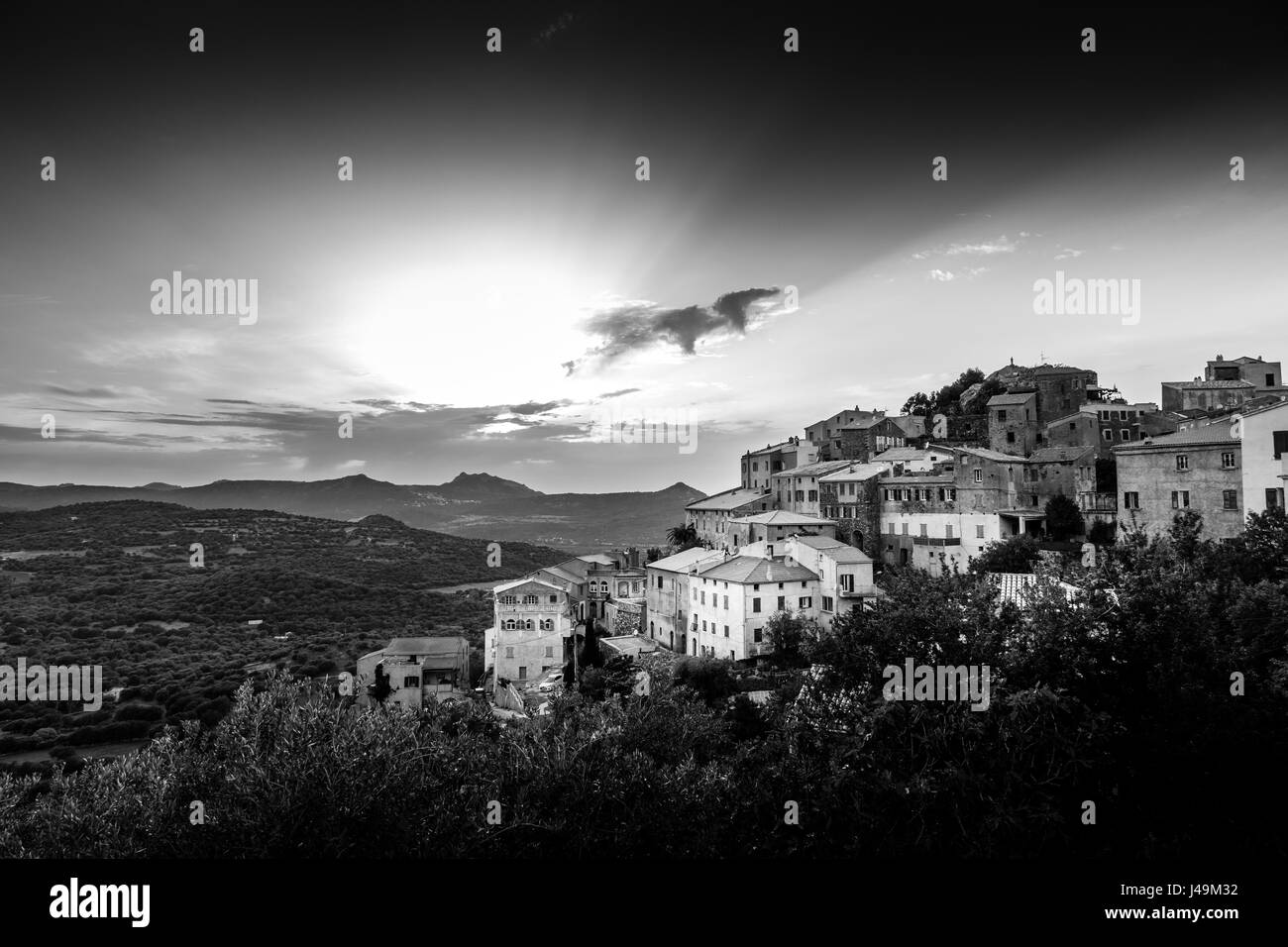 Image en noir et blanc de l'ancien village perché de Belgodere en Balagne Corse illuminée par un coucher de soleil spectaculaire Banque D'Images