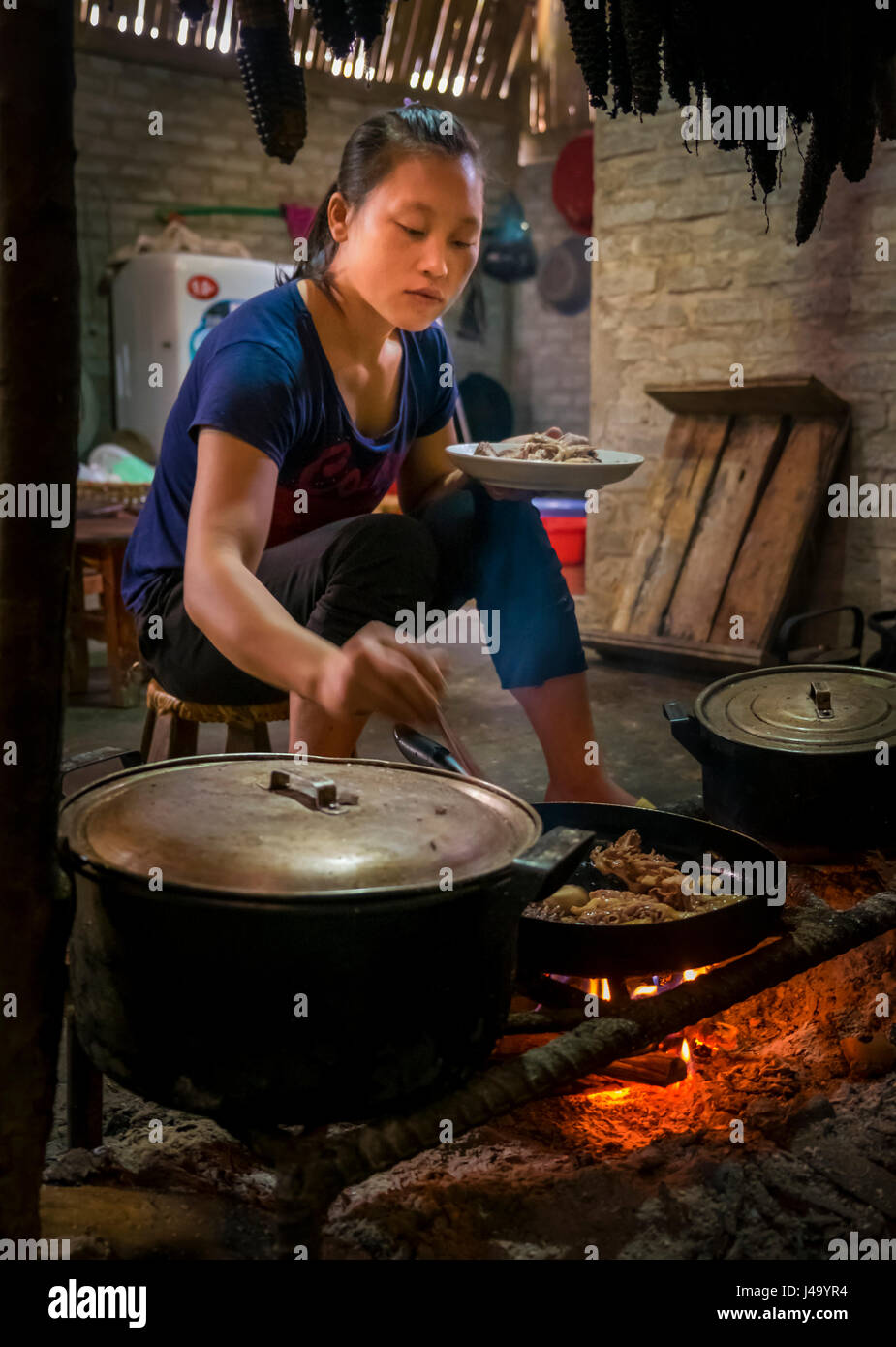 SAPA, Vietnam - CIRCA SEPTEMBRE 2014 : jeune femme de la minorité Dao rouge la cuisine dans une maison typique de la Ta Phin Village près de Sapa, Nord Vietna Banque D'Images