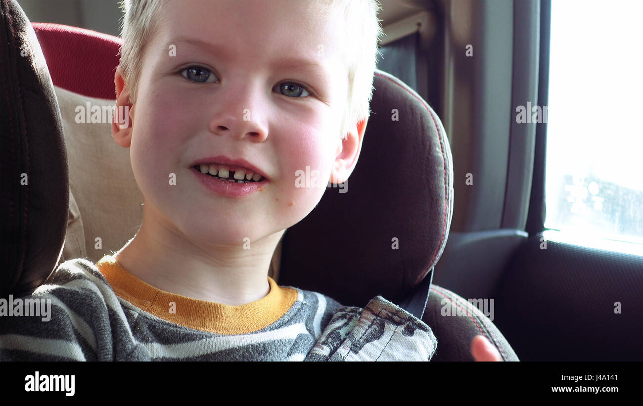 Cute boy dans un siège d'auto, sourires et rires Banque D'Images