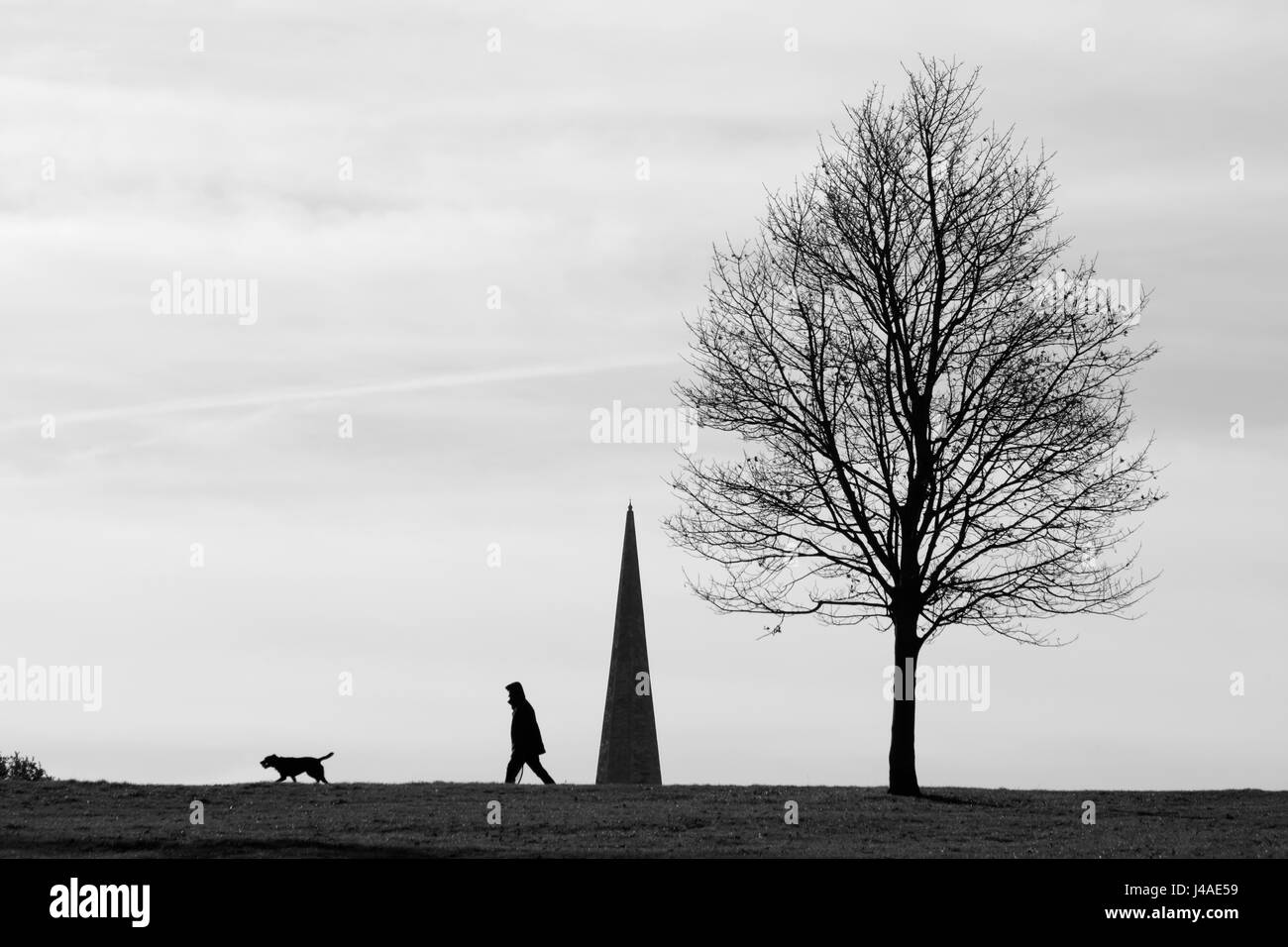 Dog walker découpé sur la flèche de l'église Holy Trinity, Brockwell Park, London, UK Banque D'Images