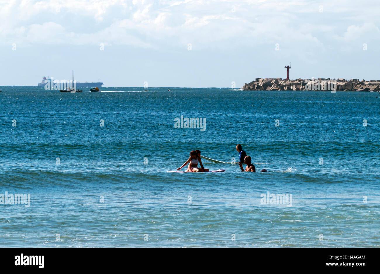 DURBAN, AFRIQUE DU SUD ; le 24 avril 2017 : matin trois surfeurs inconnus contre des navires porte-conteneurs, entrée du port et le bleu ciel nuageux à Durban, Sout Banque D'Images