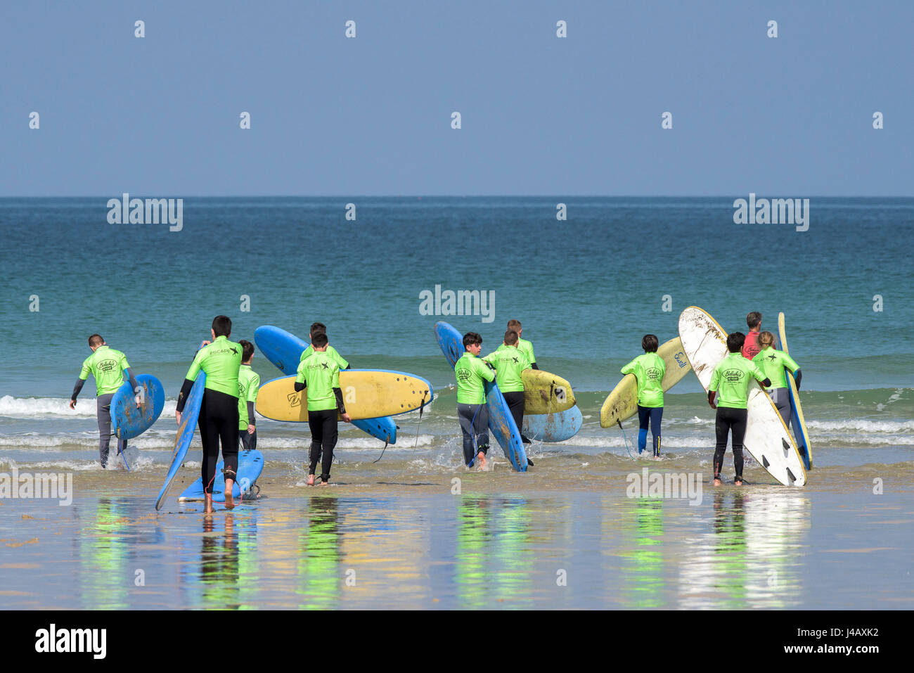 Novices à une école de surf portant leur surboards ; mer ; plage de Fistral, Newquay, Cornwall ; surf ; surf ; les apprenants ; Apprentissage, Instructeur Banque D'Images
