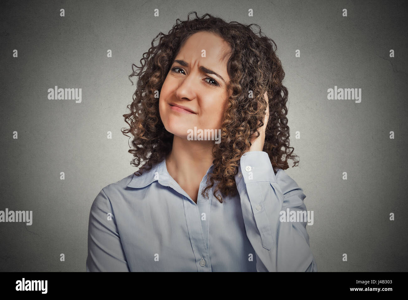 Sceptique. Femme douteuse à la caméra vous au fond de mur gris isolé. L'émotion négative de l'humain, l'expression du visage corps attitude langue sentiment Banque D'Images