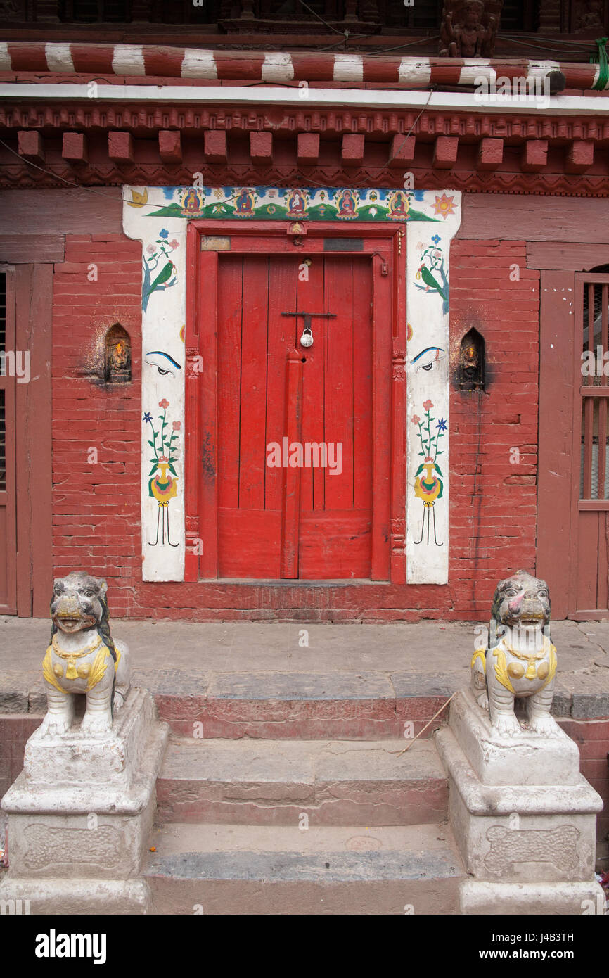 La porte rouge avec un gardien des lions et d'une tétine surround, entrée d'une maison à PATAN ou LALITPUR Kathmandu, Népal Banque D'Images