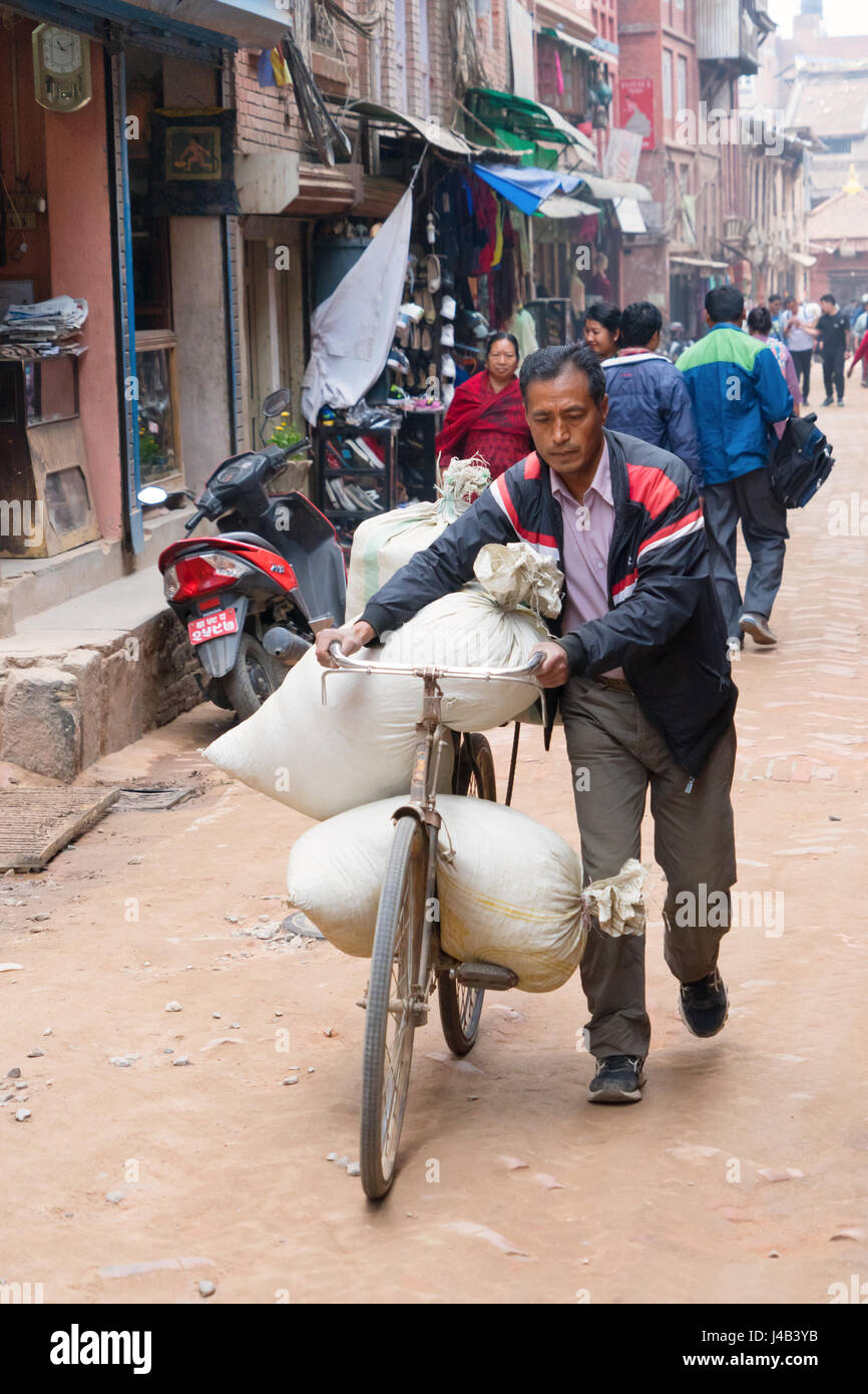 L'homme népalais offrant une charge lourde sur son vélo à Bhaktapur, Népal. Banque D'Images