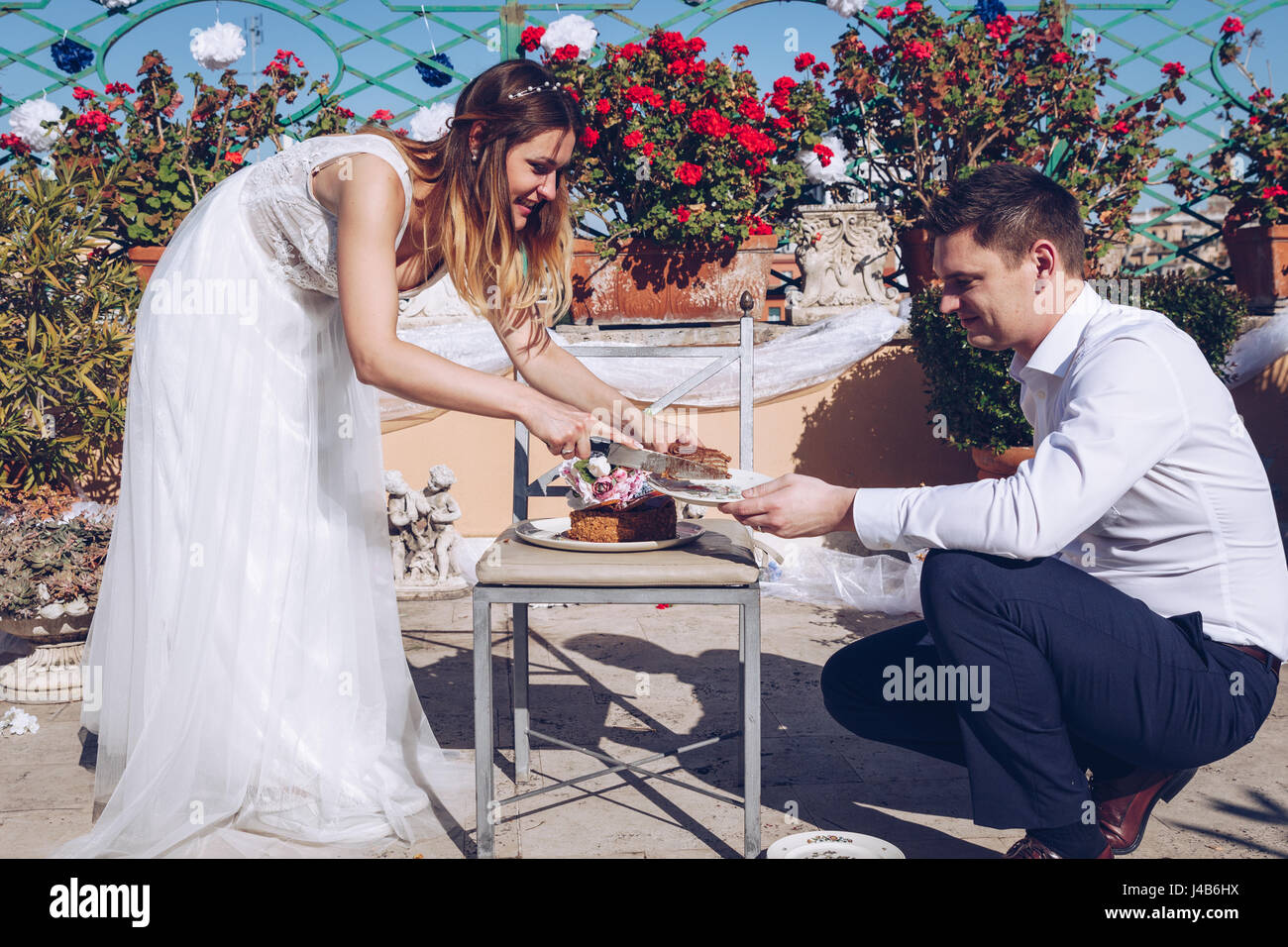 Salon de la mariée et le marié sont beau découpage d'un gâteau de mariage. Couple sur la terrasse avec la ville de Rome dans l'arrière-plan. Beau modèle girl in white Banque D'Images