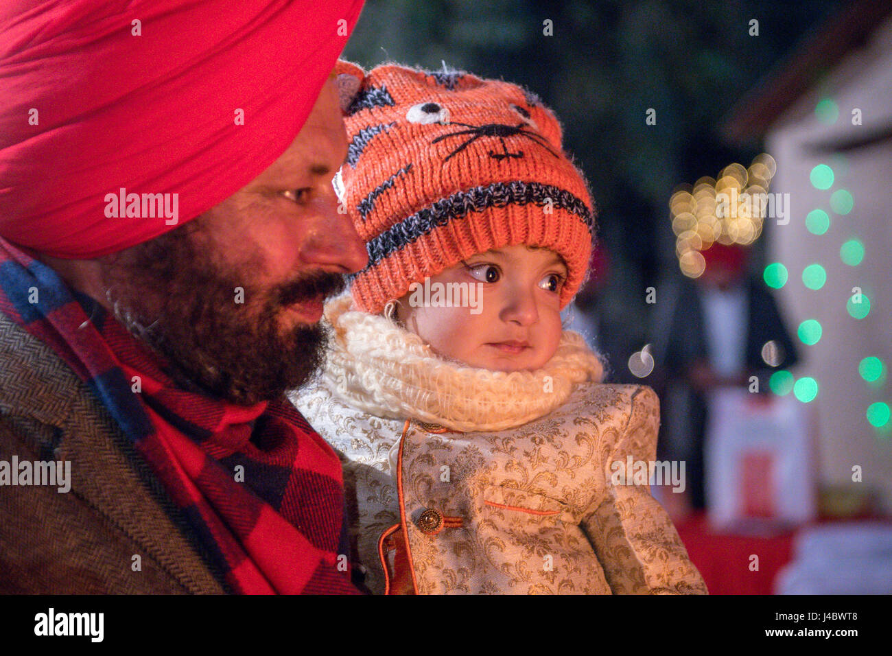 Un jeune enfant regarde dans la lumière du feu de camp à l'Lohri célébration dans la province du Punjab, en Inde. Banque D'Images