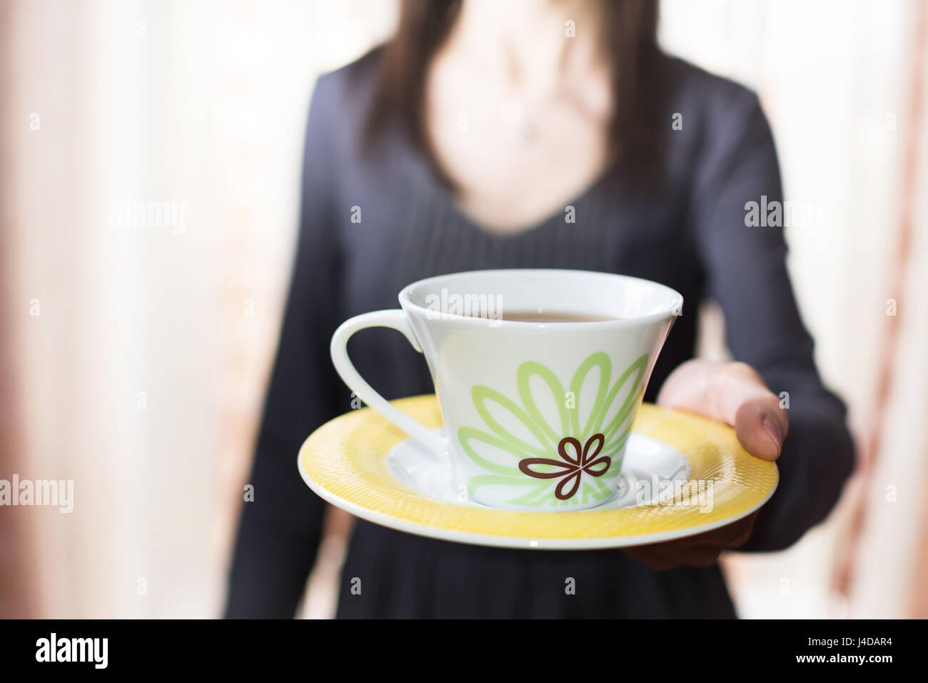 Femme offrant une tasse de thé (FLOU) Banque D'Images