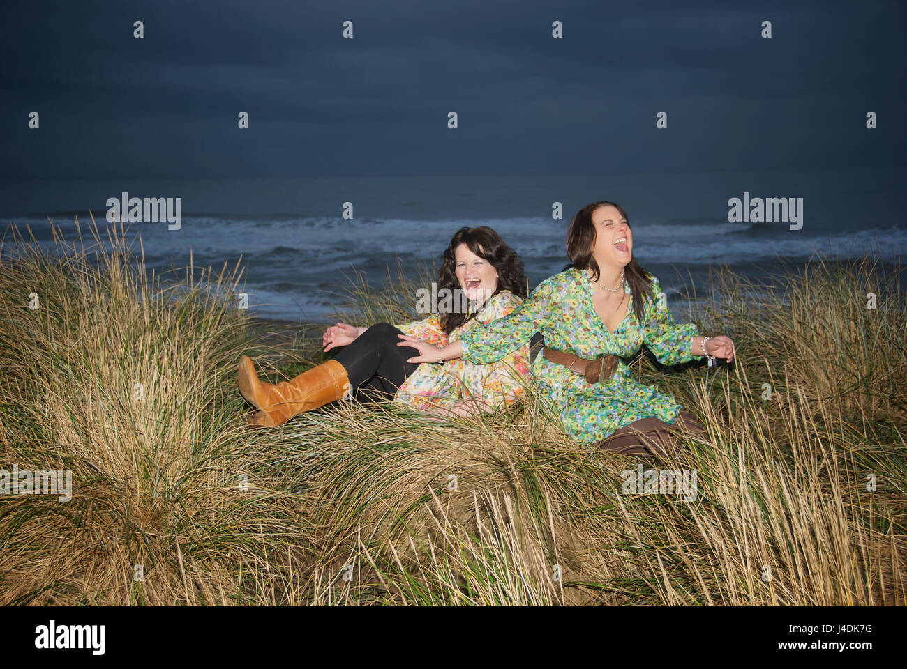 Deux filles rire dans les dunes de sable par la mer sur un après-midi orageux Banque D'Images