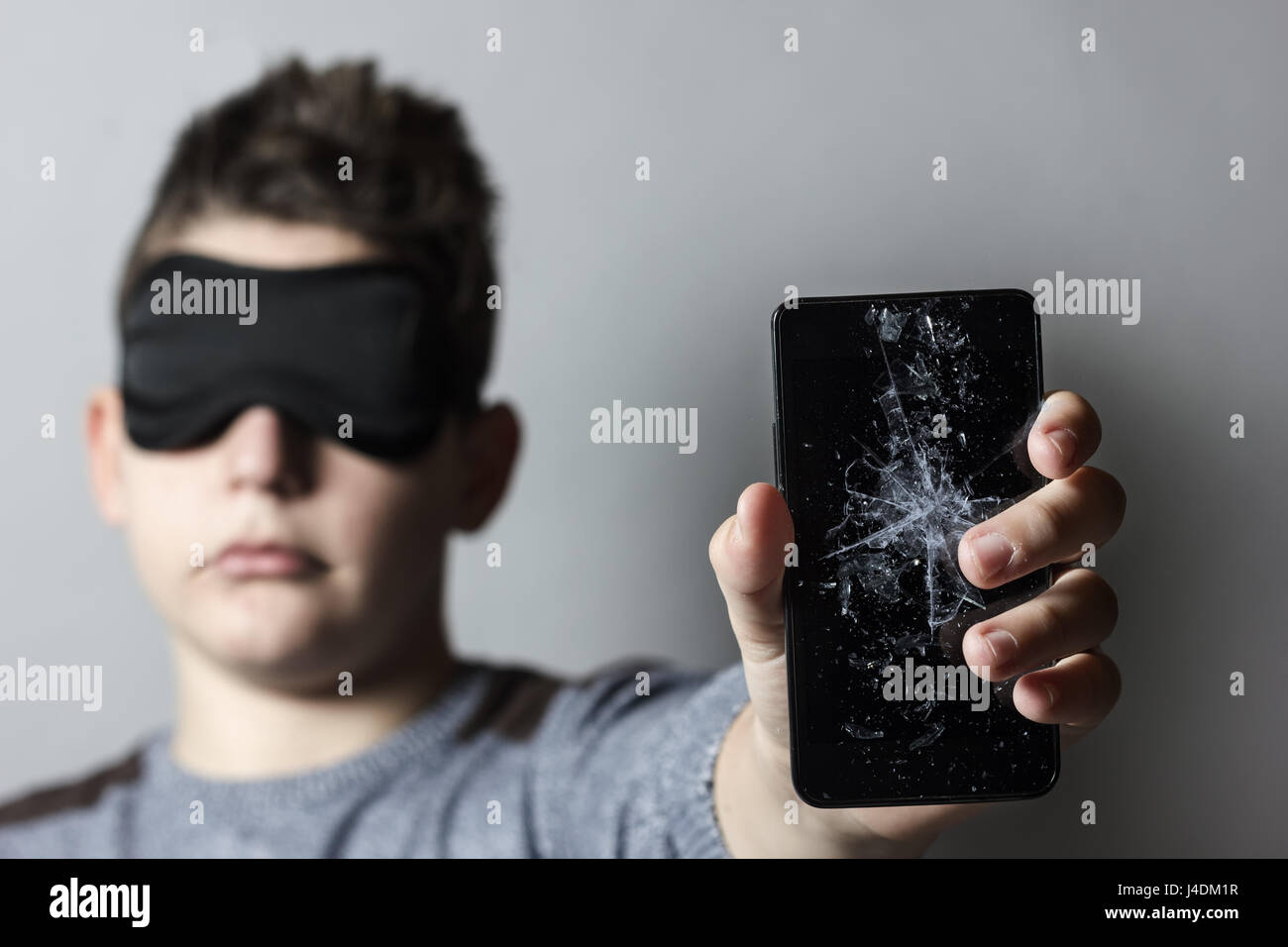 Triste de l'adolescence est inquiète suite de bris de verre smart phone en face de fond gris Banque D'Images