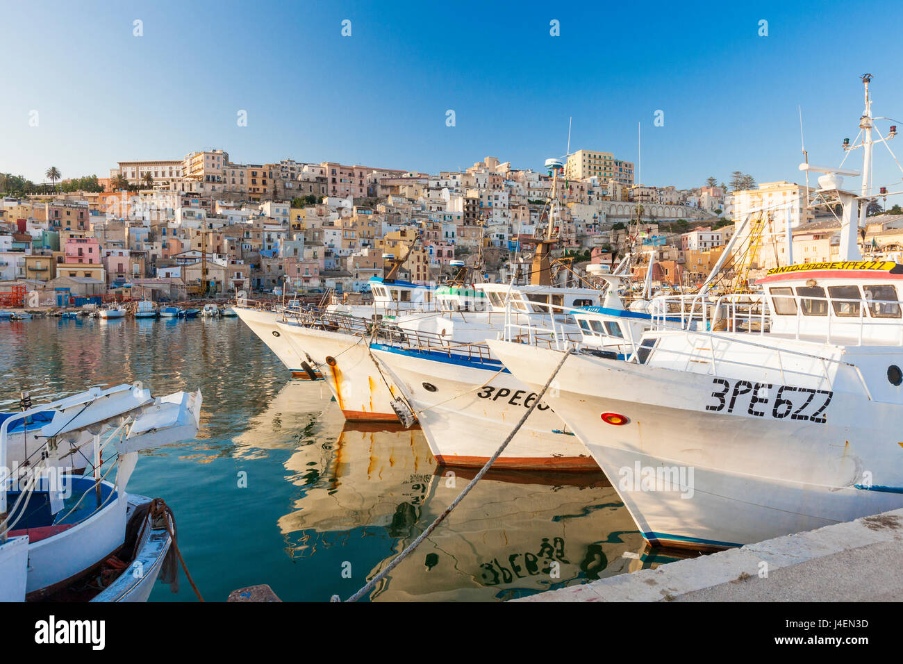 Les bateaux de pêche amarrés dans le port entouré de bleu de la mer et de la vieille ville, Sciacca, Province d'Agrigente, Sicile, Italie Banque D'Images
