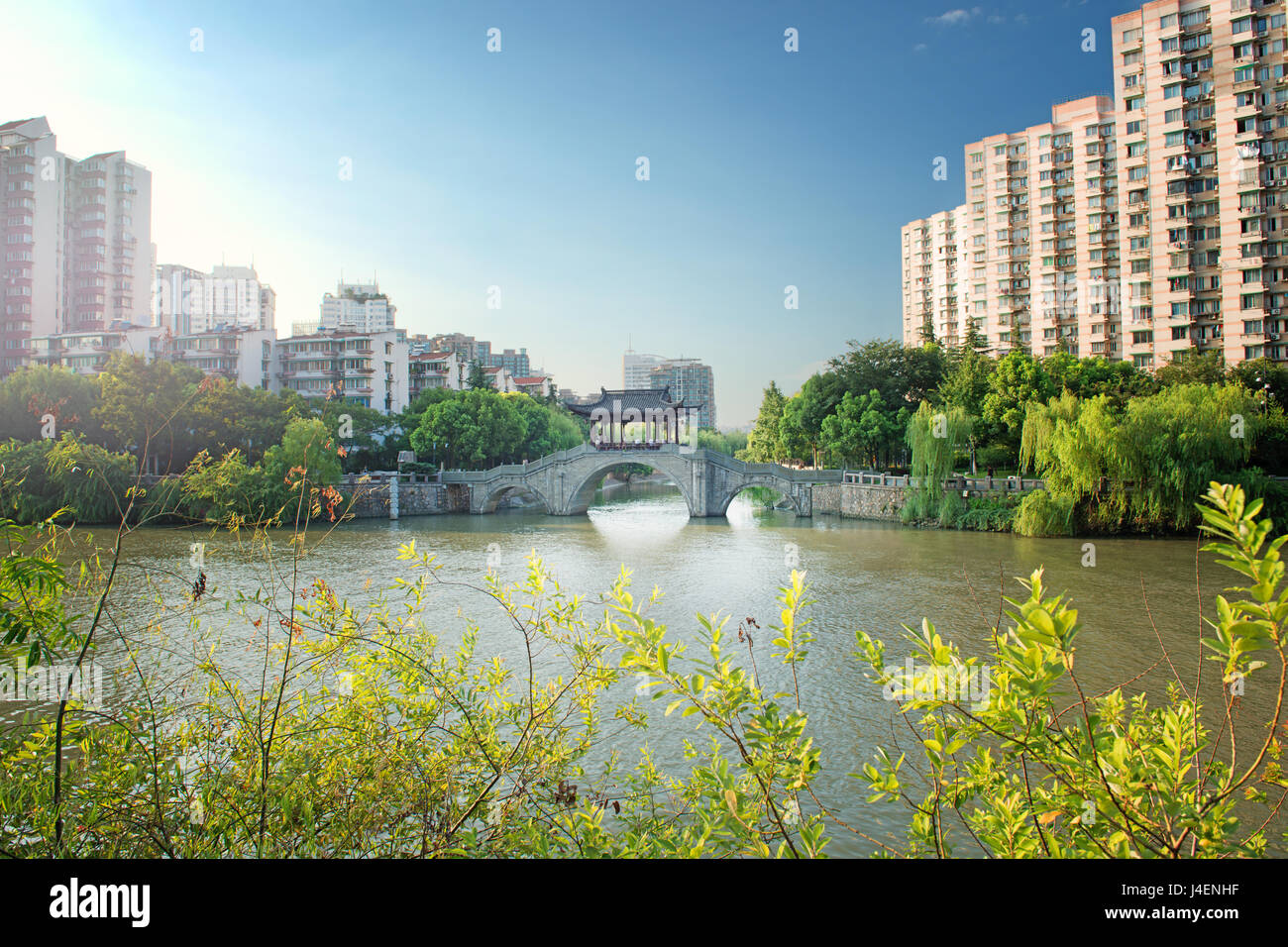 Pont en pierre avec toiture de style pagode, flanquée par de vieux immeubles de style sur la gauche, Hangzhou, Chine Banque D'Images