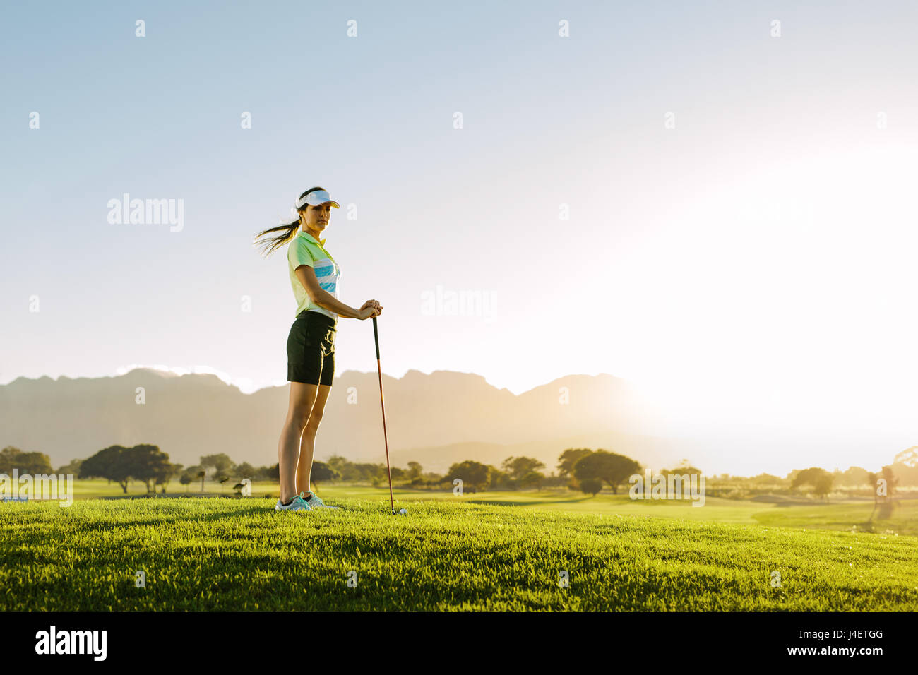 Toute la longueur de golfeuse de race blanche debout sur le parcours de golf. Champ de golf sur une journée ensoleillée. Banque D'Images