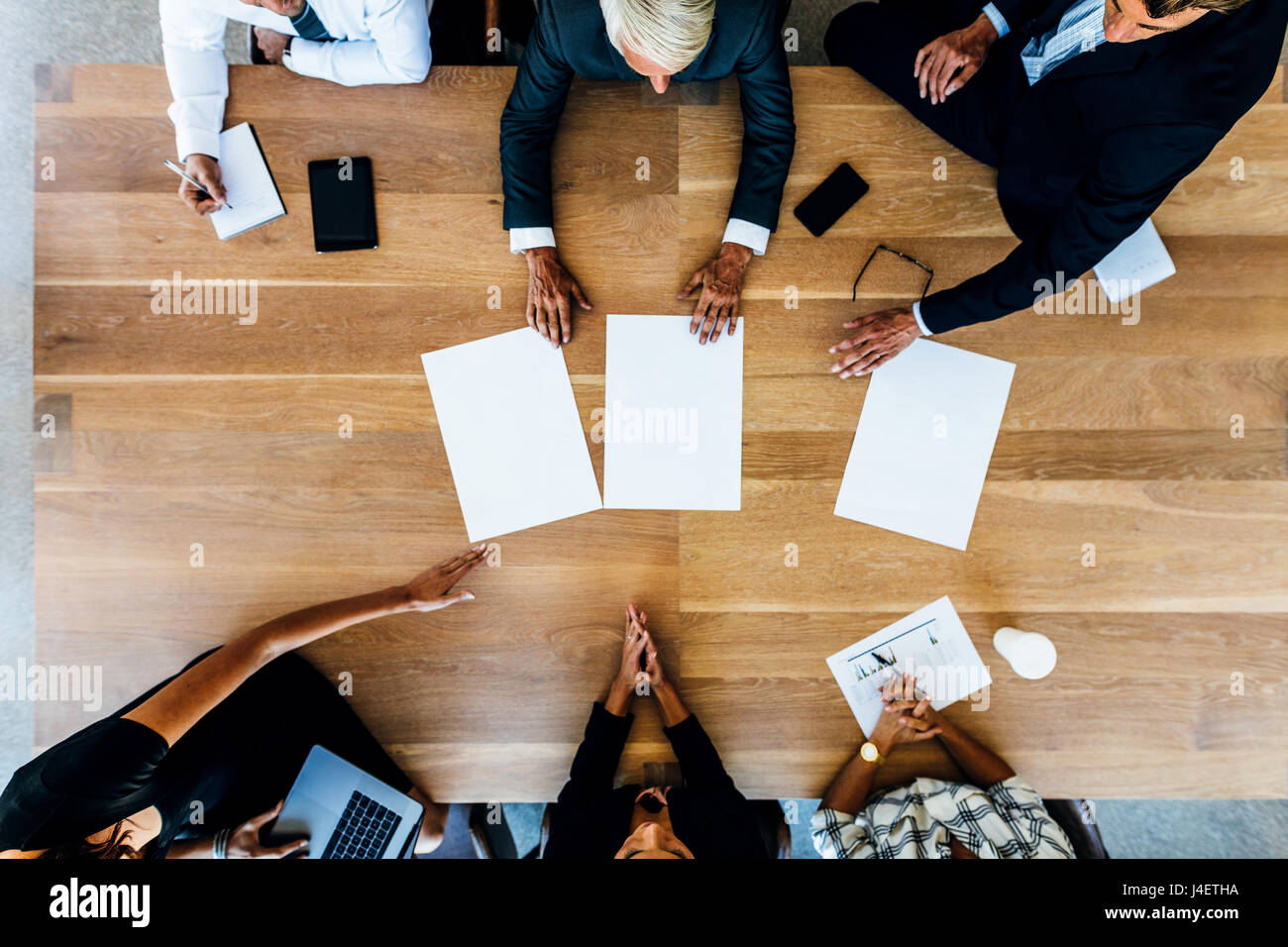 Groupe de personnes plaçant des plaques vierges sur table. Vue de dessus de gens d'affaires ayant une réunion. Banque D'Images