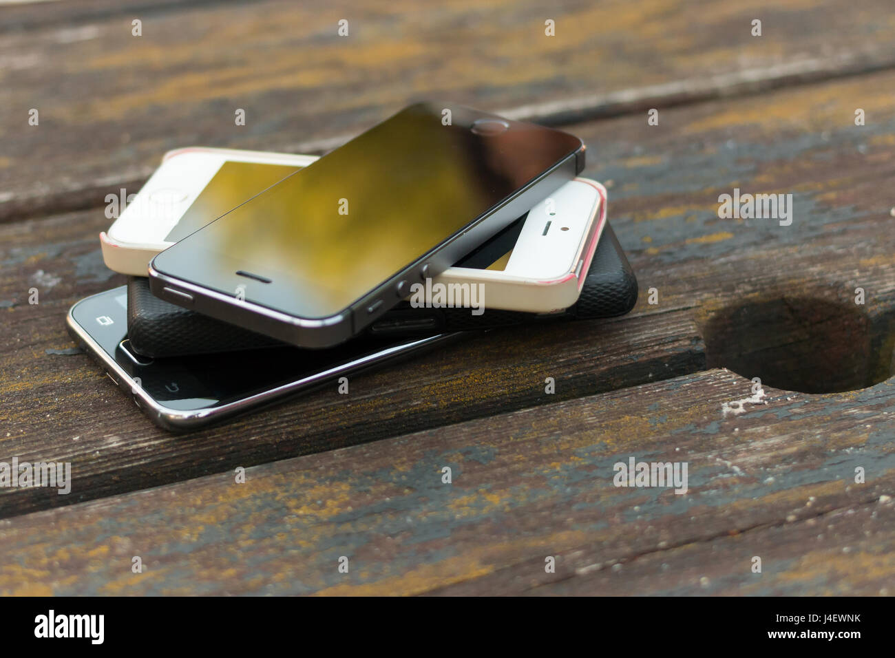 Une pile de téléphones intelligents à l'extérieur sur une table de pub. Banque D'Images