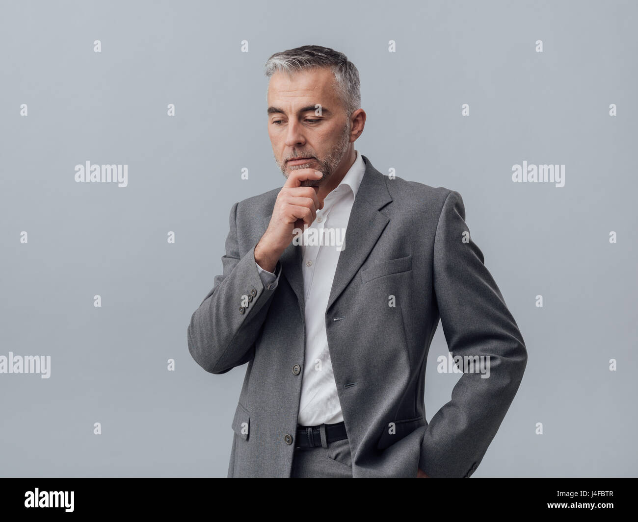 Pensive businessman thinking with hand on chin, stratégies d'entreprise concept Banque D'Images Pensive businessman thinking with hand on chin, stratégies d'entreprise concept Banque D'Images