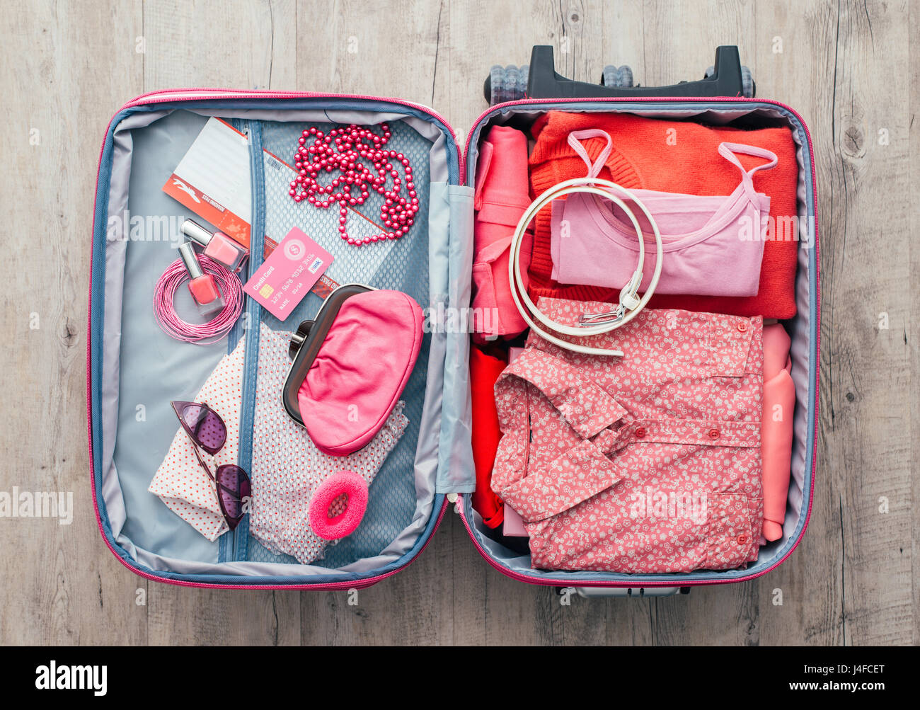 La femme sac ouvert sur un bureau avec les vêtements et accessoires, elle est l'emballage et se préparer à partir, voyage et vacances concept Banque D'Images