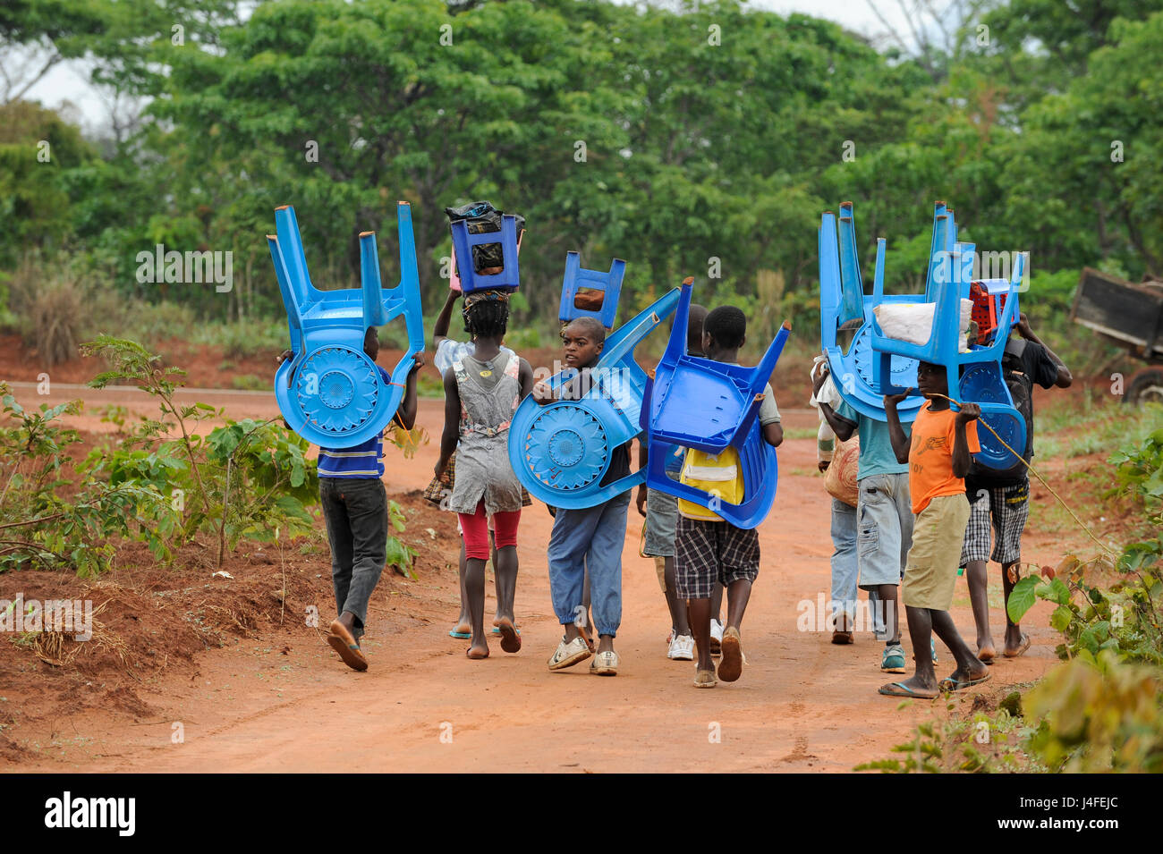 ANGOLA Kwanza Sul, village Kassombo, les enfants sur le chemin de l'école, chaque enfant doit apporter son propre fauteuil en plastique comme les écoles en mauvais état en raison de la guerre civile et la corruption, les recettes provenant de l'Angola, riche en pétrole ne semble pas atteindre les villages / ANGOLA Kwanza Sul, Dorf Kassombo, Kinder mit Plastikstuehlen auf dem Weg zur Schule durch Felder des Dorfes, da die Schulen durch den Buergerkrieg zerstoert Inventar und ohne sind, muss jedes genre seinen Plastik Stuhl mitbringen Banque D'Images