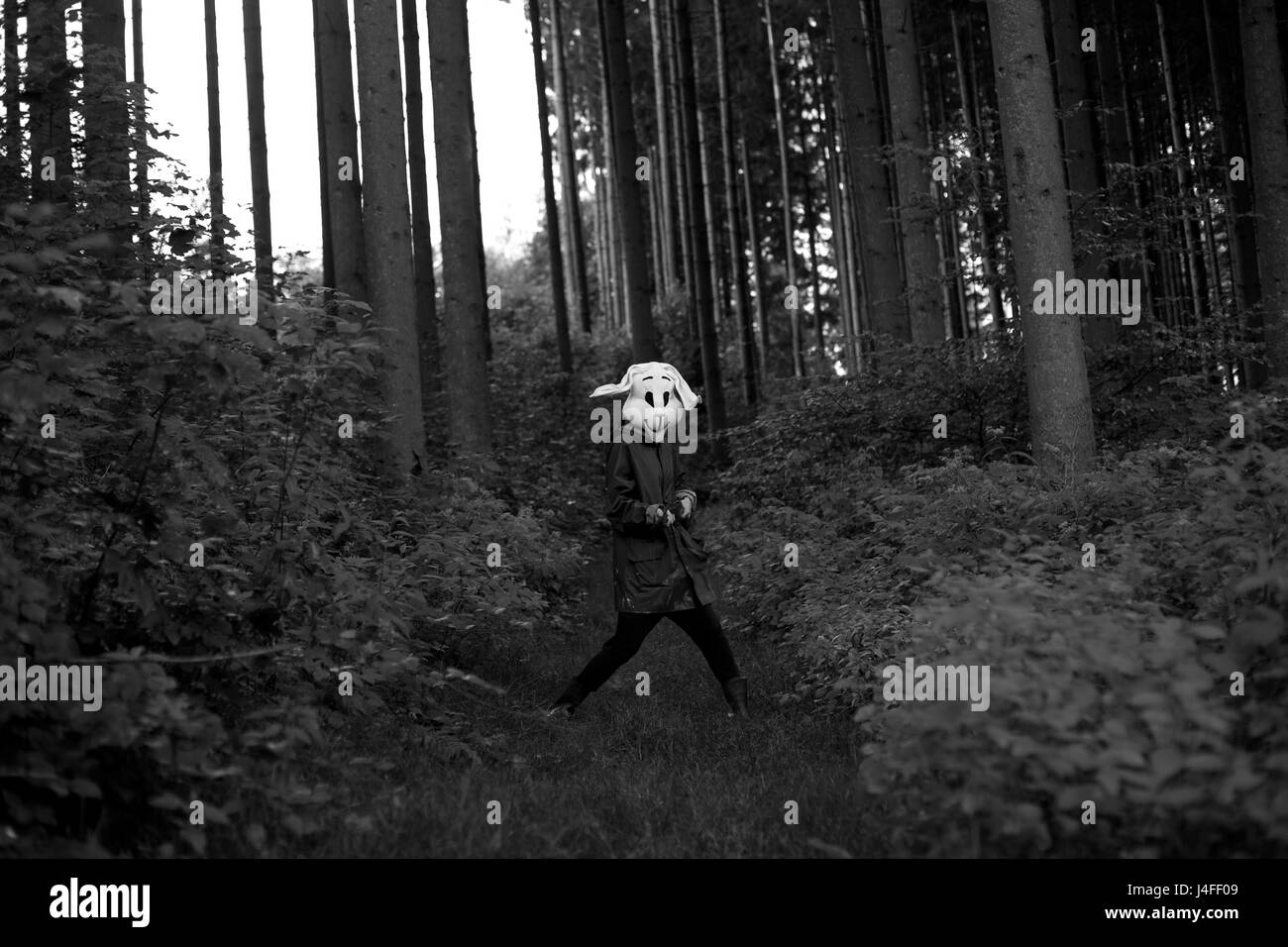 La photographie en noir et blanc. femme portant un masque de lapin chasseur avec fusil de chasse dans une forêt Banque D'Images