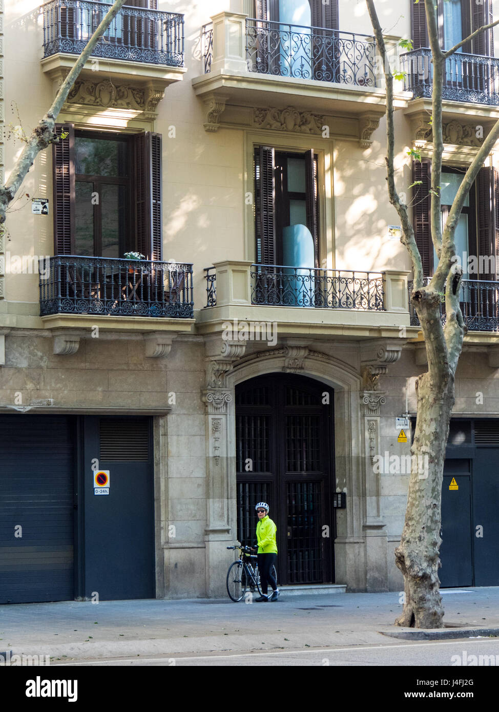Une femme cycliste avec son vélo debout en face d'un bloc d'appartement dans l'Eixample, Barcelone, Espagne. Banque D'Images
