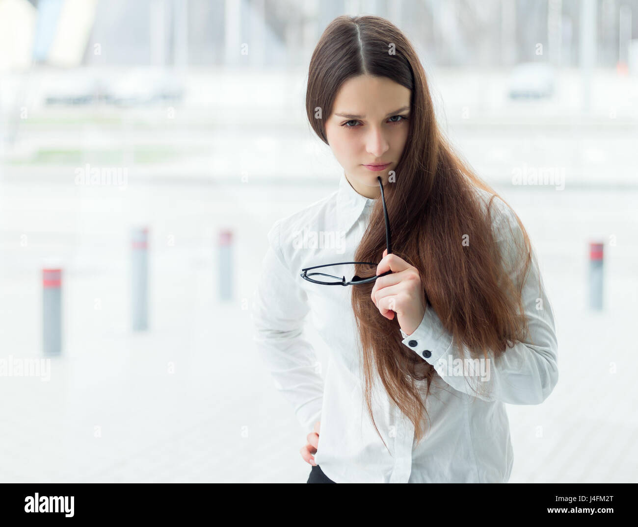Young business woman standing in office tenir lunettes. Jeune femme manager portrait. Banque D'Images