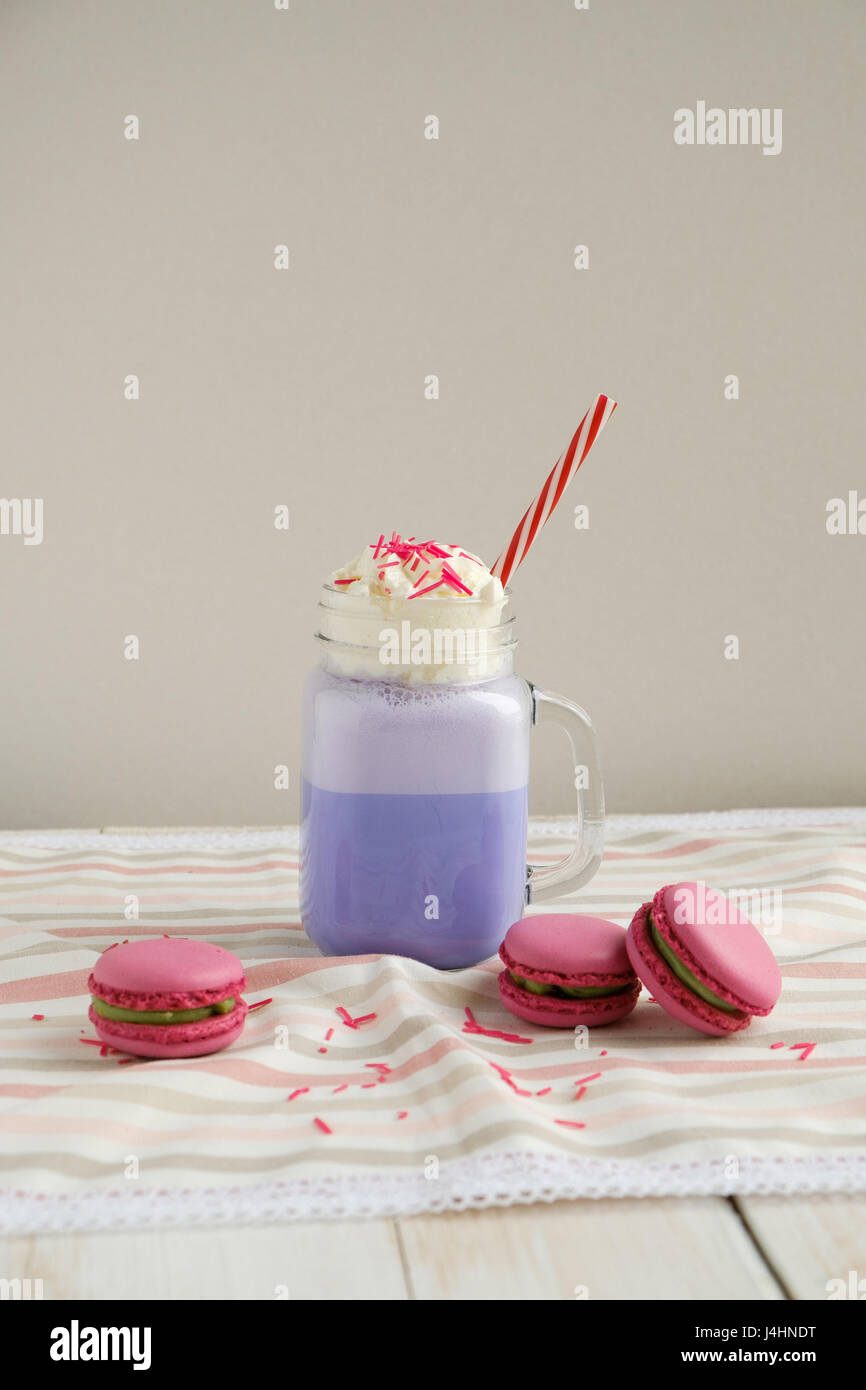 Café pourpre en pot Mason Tasse stylisée avec ses macarons et une décoration colorée. Lait frappé aux bleuets. Café Unicorn. L'alimentation Unicorn Banque D'Images