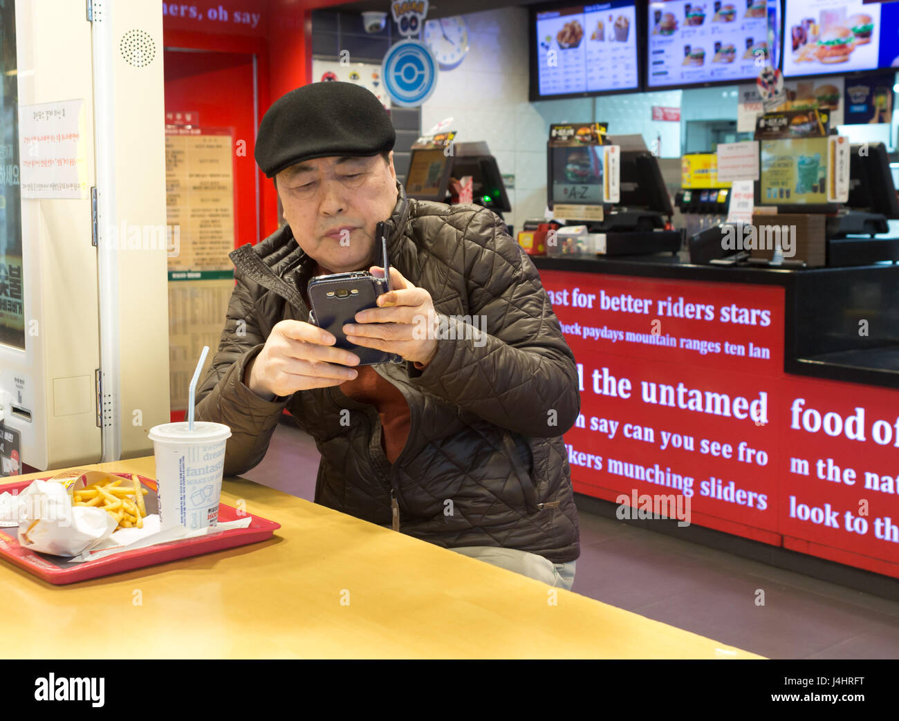 Busan, Corée du Sud - Mars 27th, 2017 sud-coréen : homme à l'intérieur d'un fast-food à son mobile. Banque D'Images
