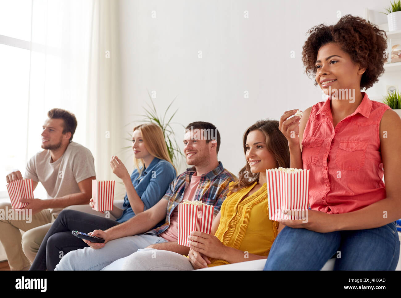 Happy friends with popcorn devant la télé à la maison Banque D'Images