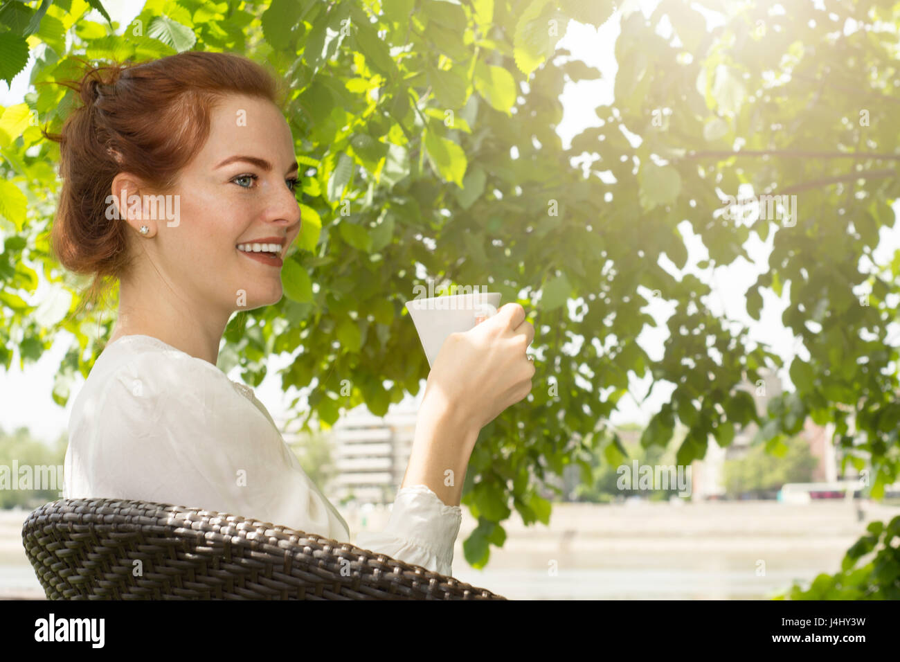 Redhead Woman drinking coffee piscine en plein soleil, appréciant son café du matin. Banque D'Images