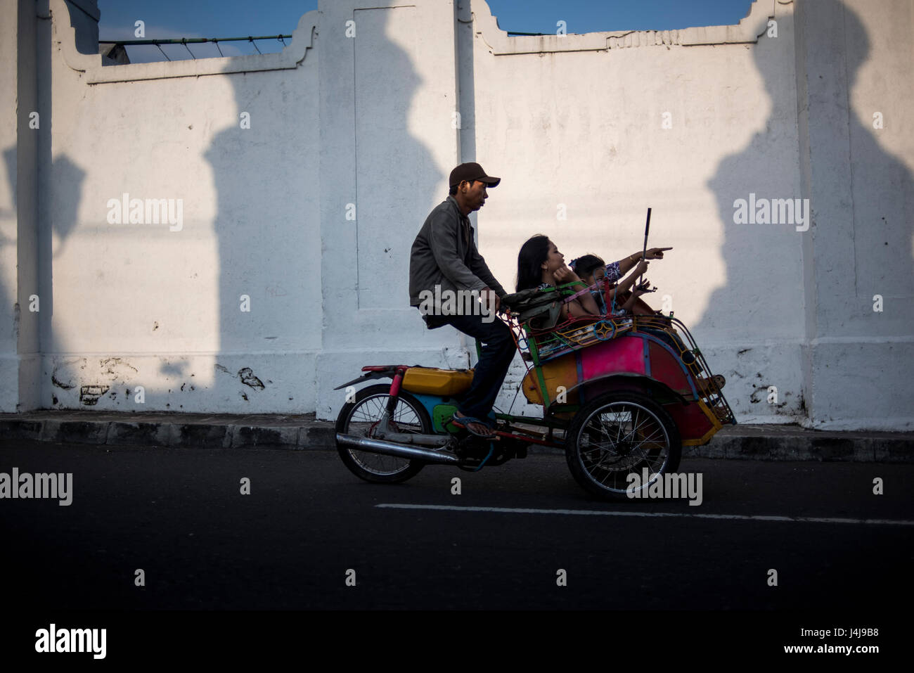 Les clients d'un conducteur de pousse-pousse dans la ville de Yogyakarta, Java, Indonésie. Banque D'Images
