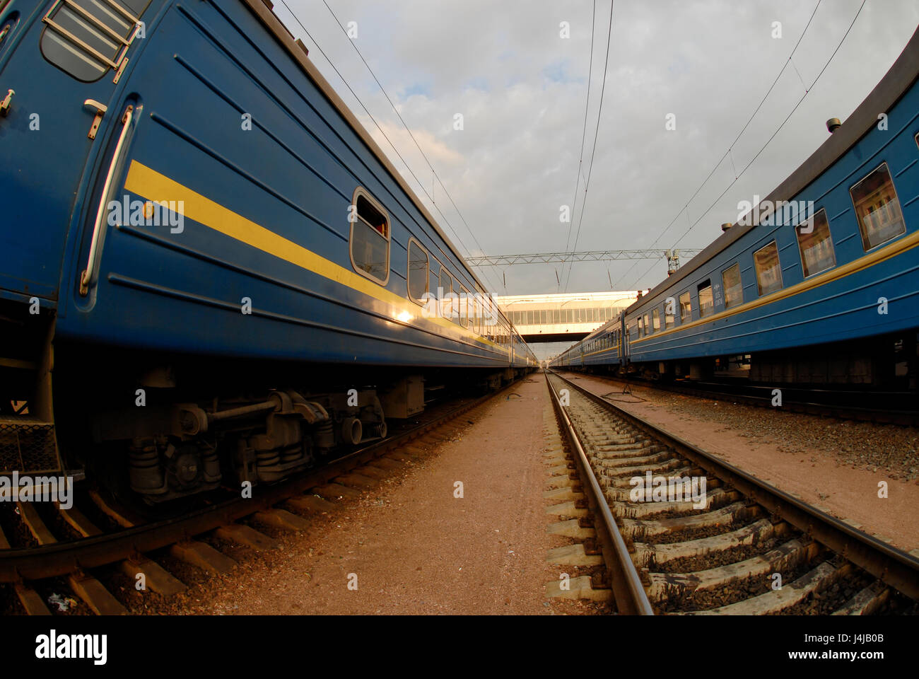 Deux trains avec wagons bleu et entre eux, tous les rails convergent pour un point de l'horizon. Banque D'Images