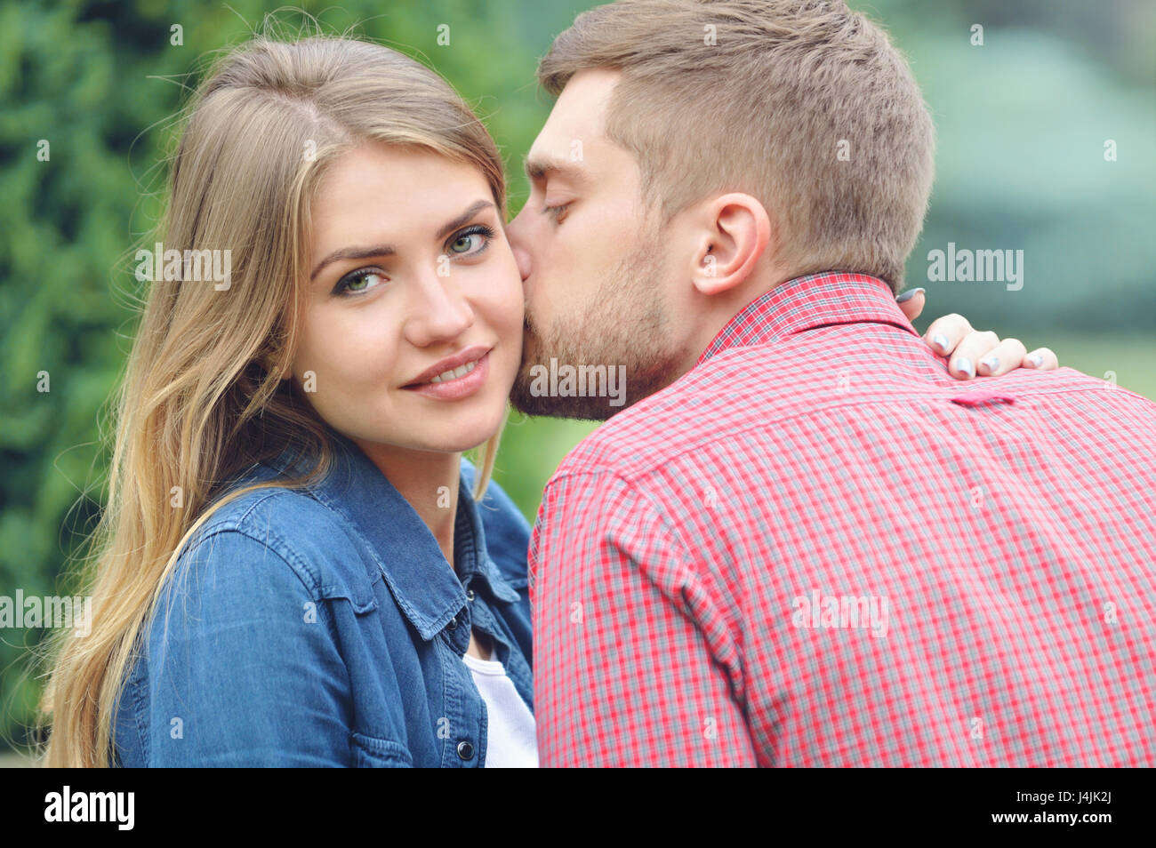 Jeune fille belle à regarder pendant que l'appareil photo d'être embrassé par son petit ami. Close up portrait. L'amour, relation, famille et personnes concept - smiling Banque D'Images