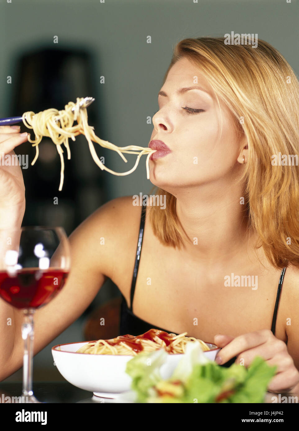 Femme, manger des spaghettis, demi-portrait restaurant, robe de fête, Pinafore, salade, plat de pâtes, nouilles, wineglass, vin, vin rouge, à l'intérieur, de la consommation, de l'apprécier Banque D'Images